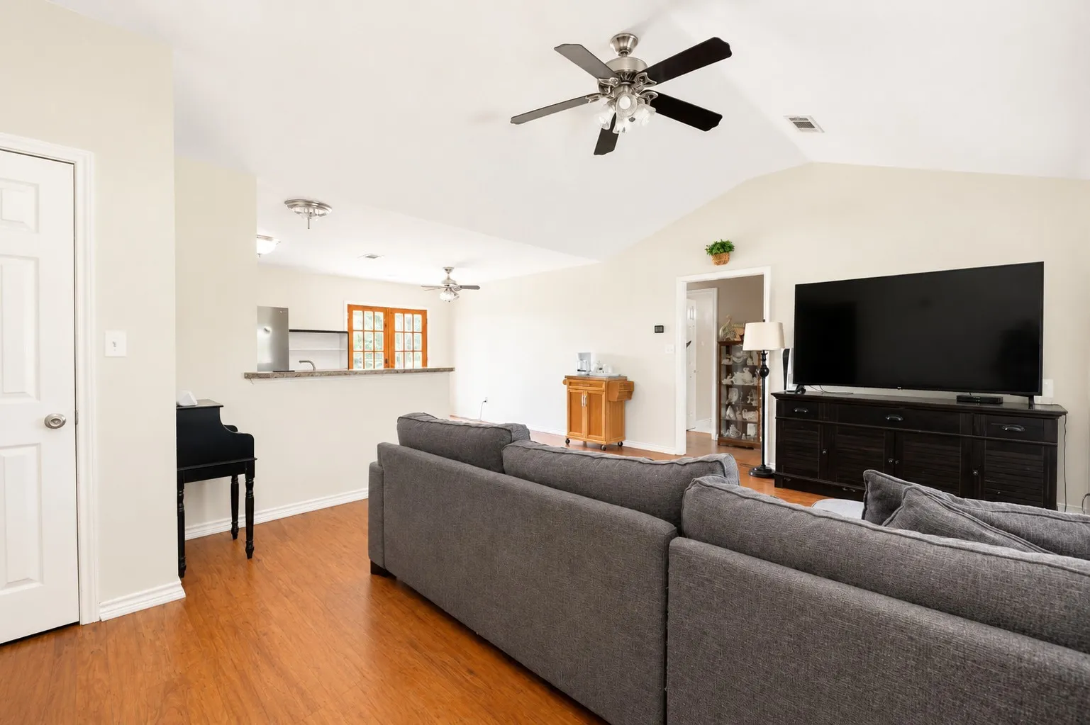 Vaulted ceiling, wood-finish flooring, built-in breakfast bar, interior French doors, and ceiling fans