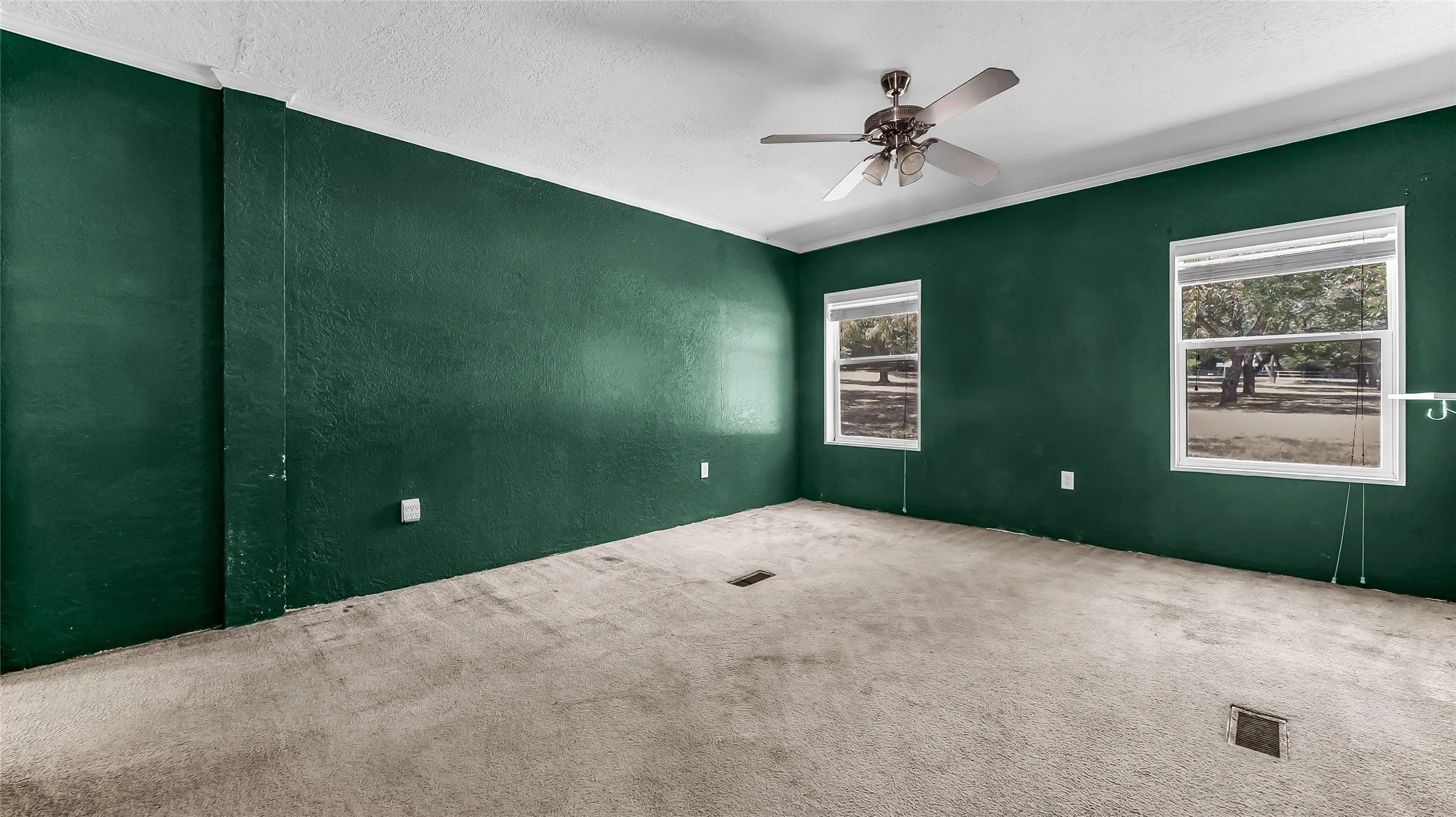 Ceiling fan with brushed nickel finish, two windows, and textured walls