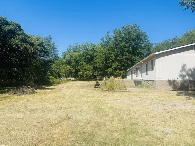 Expansive outdoor area with a lawn, mature trees, and an expansive deck