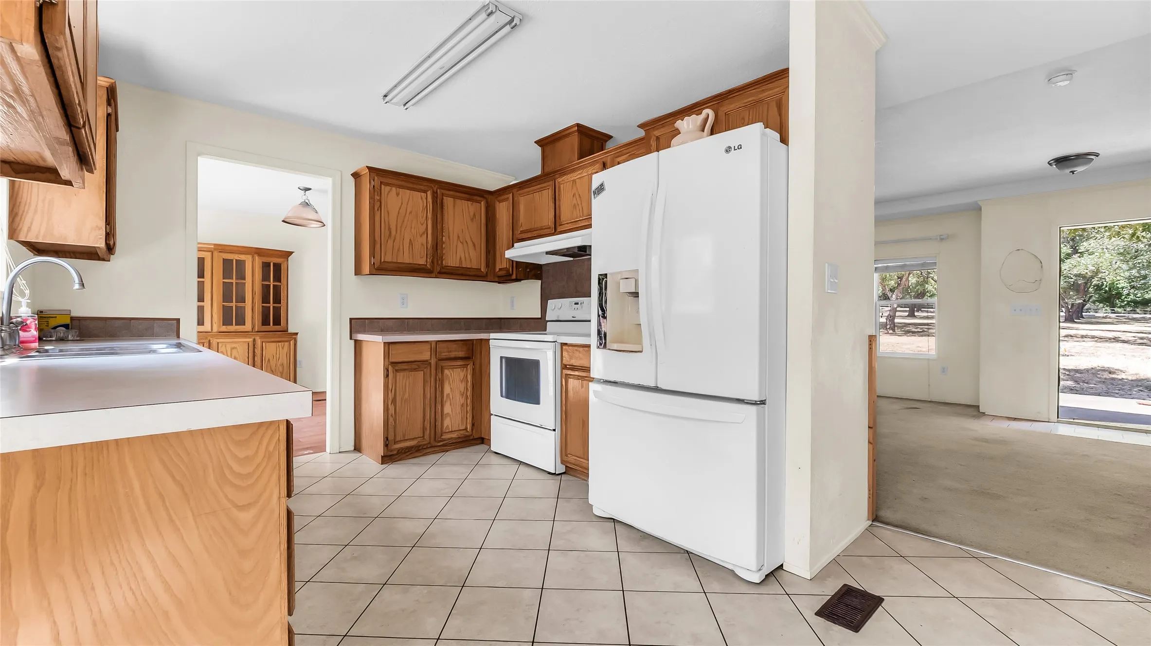 Kitchen featuring wood cabinetry, white appliances, and tiled flooring
