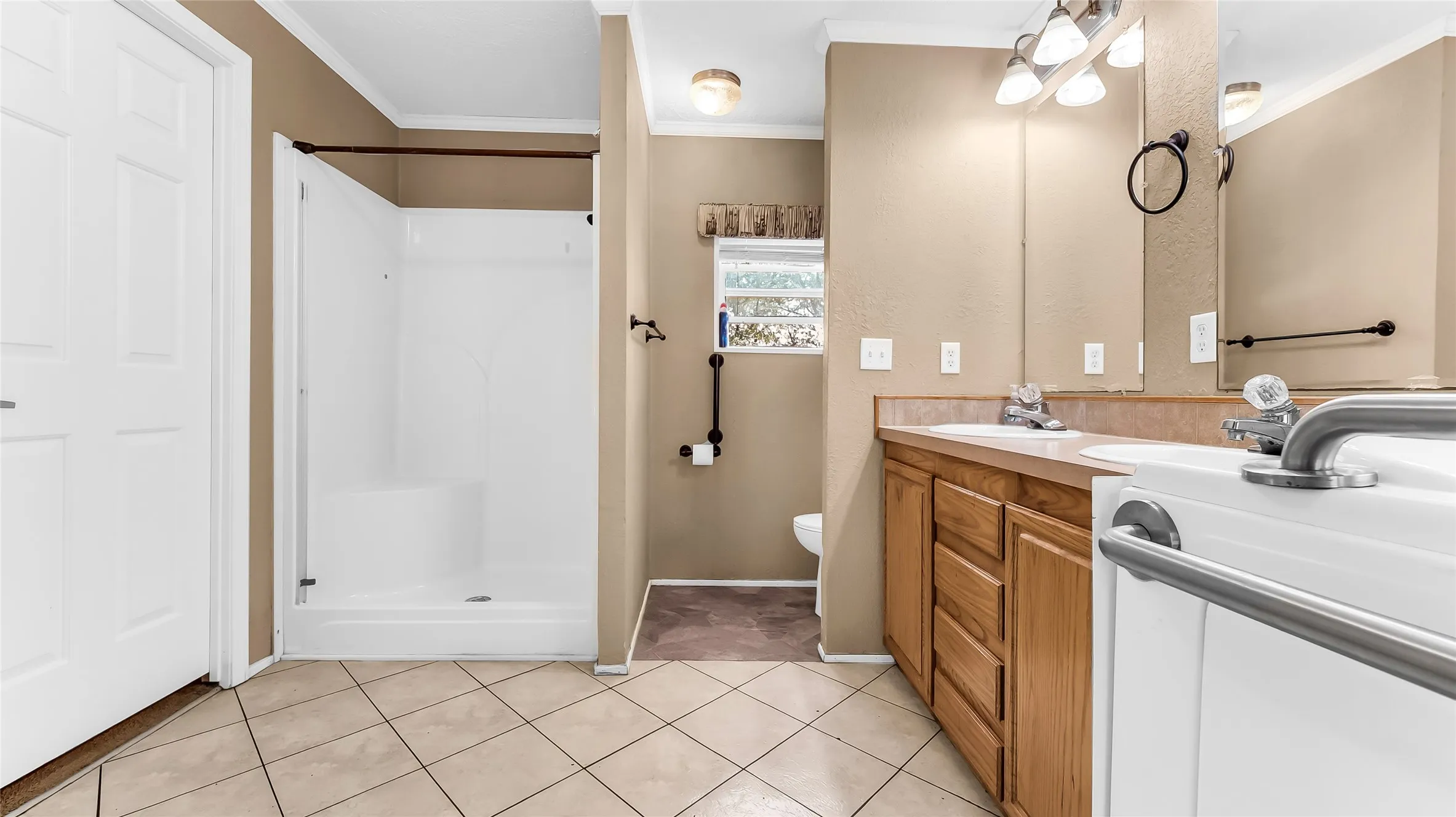 Tiled flooring, double vanity with wood-finish cabinetry, built-in shower, recessed lighting, and a garden tub with grab bars