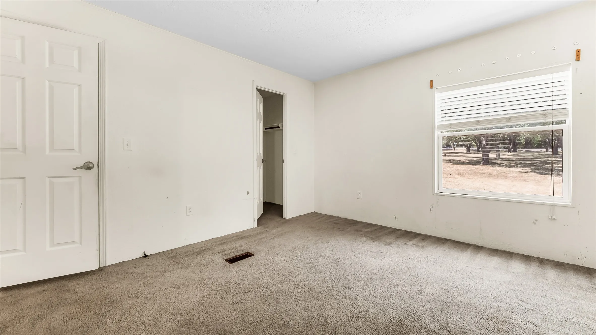 Carpeted flooring, white interior walls, and a window with blinds