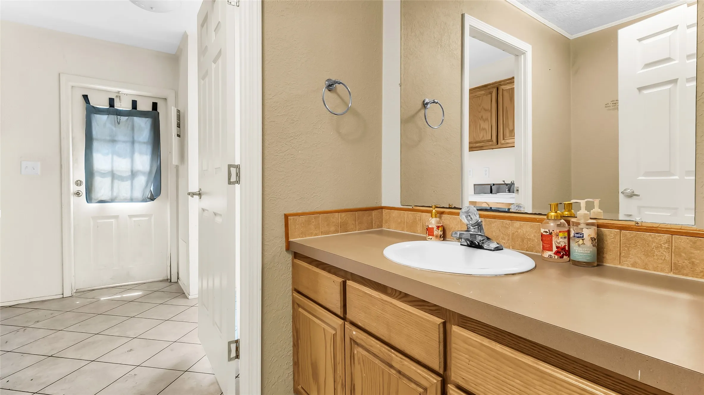 Vanity with a built-in sink, wood-finish cabinetry, and a full-width mirror