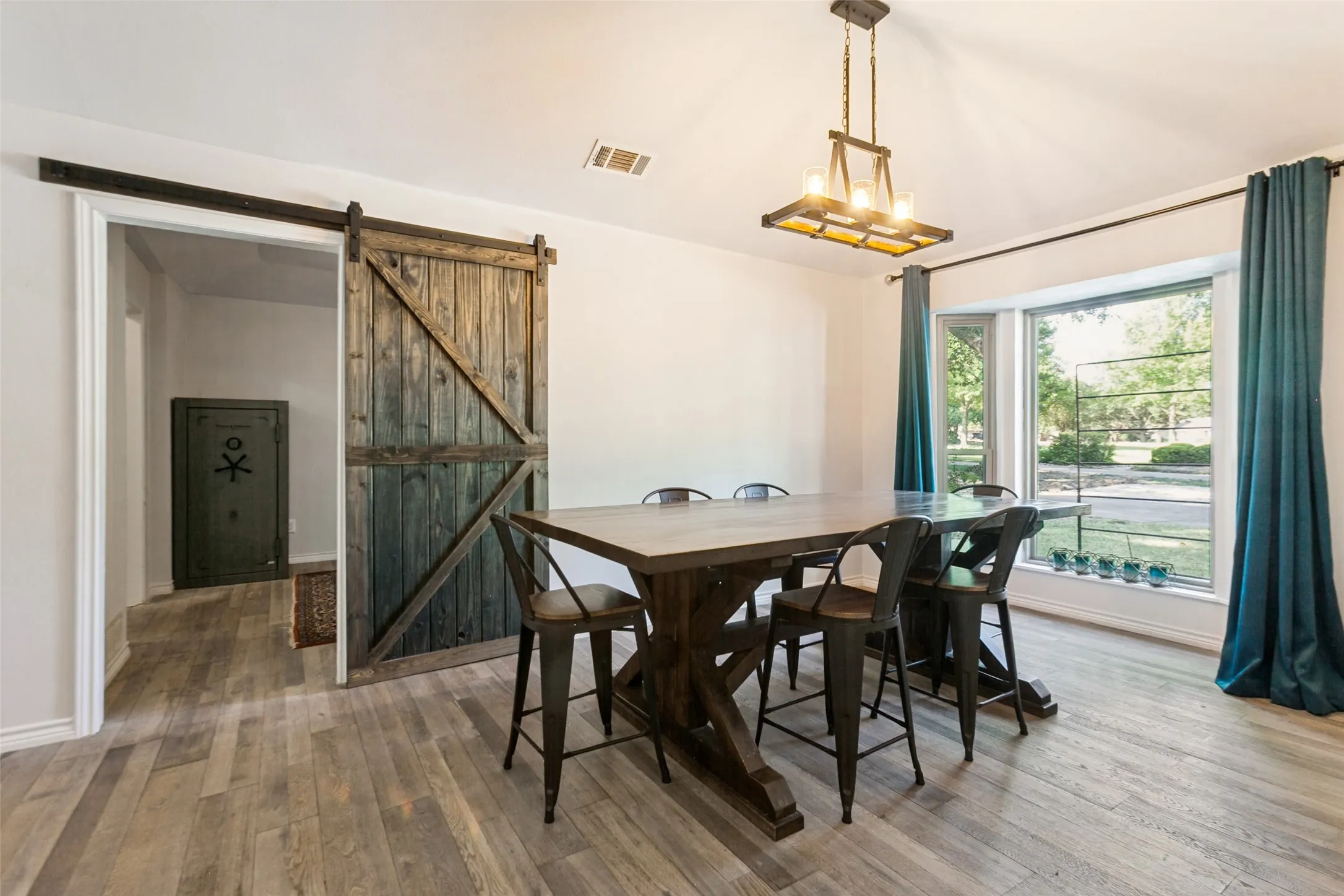 Wood-finish flooring, a wood barn door, and an overhead chandelier with exposed bulbs