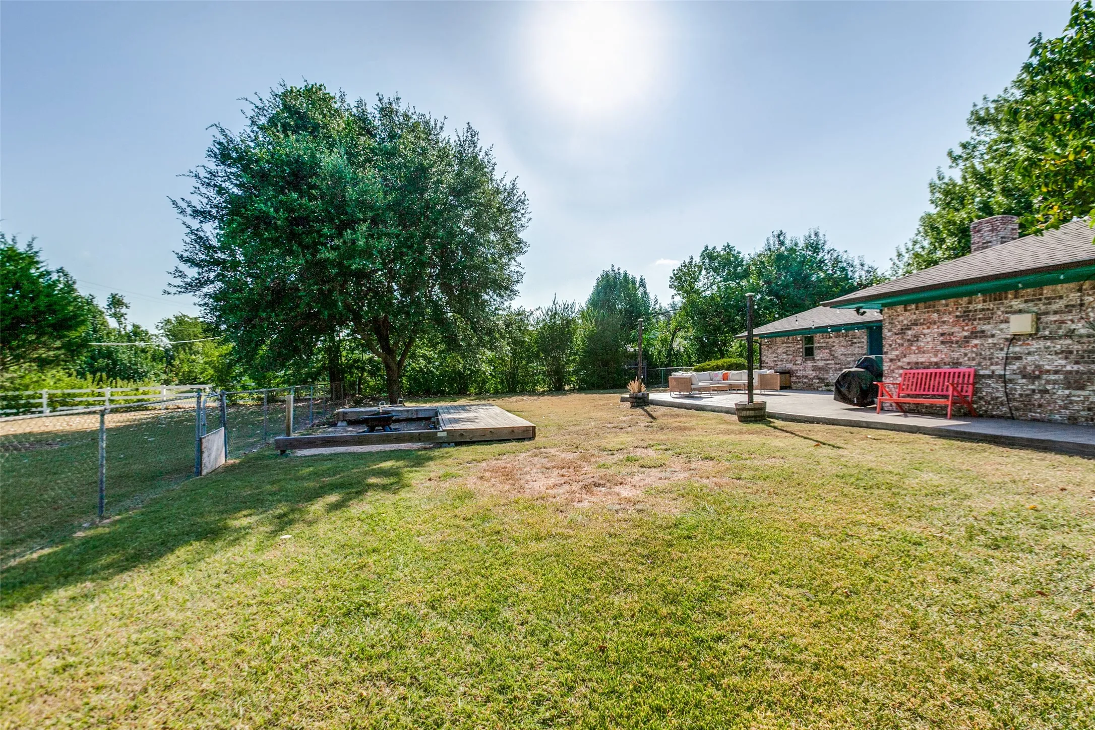 Expansive green space with mature trees, a chain-link fence, and a brick-clad exterior