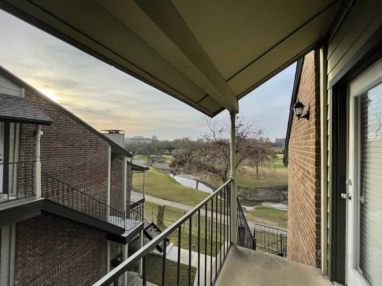 Balcony overlooking a landscaped area with water features and distant buildings