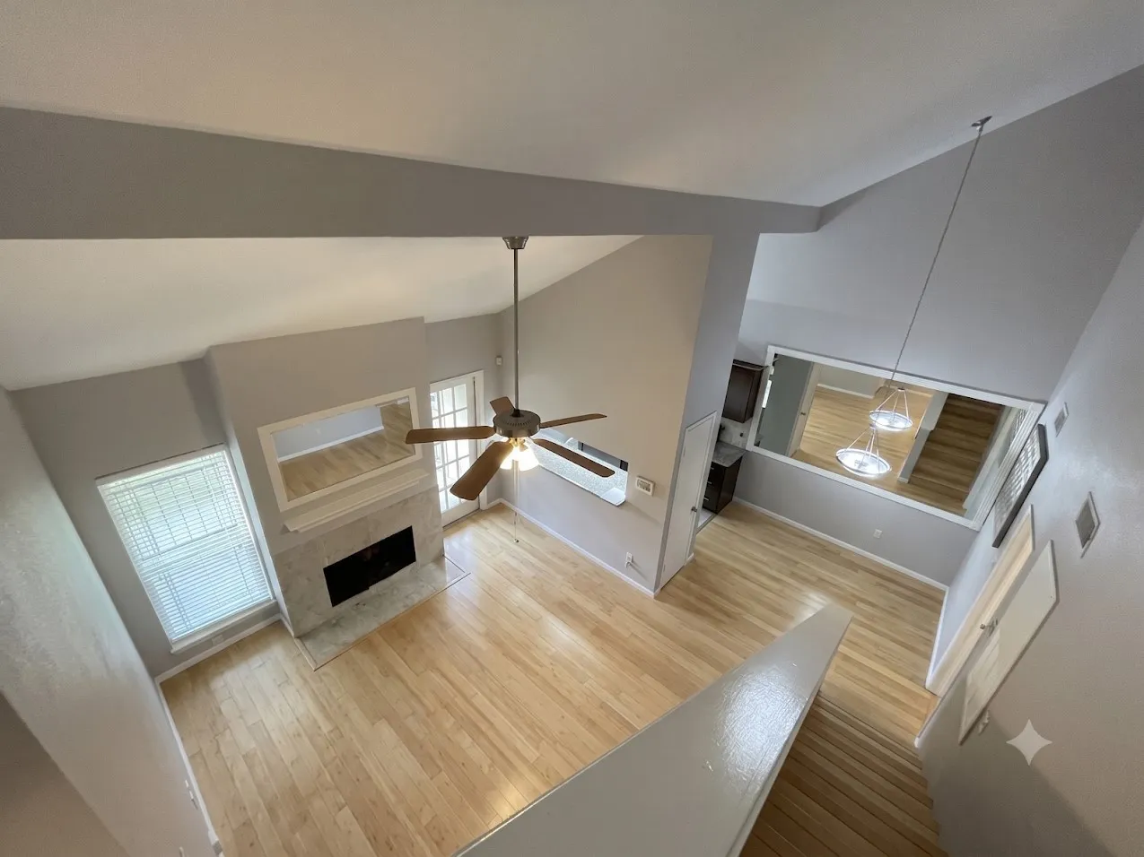 Vaulted ceilings, wood-finish flooring, fireplace with stone surround, ceiling fan, and staircase with wood treads