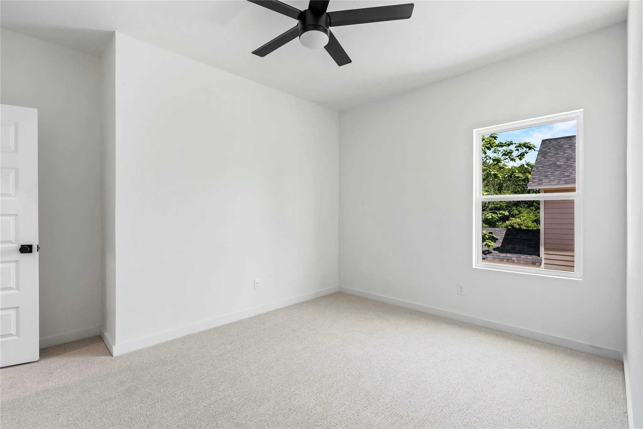 Light-colored wall-to-wall carpeting, white walls, white trim, and a ceiling fan with black blades