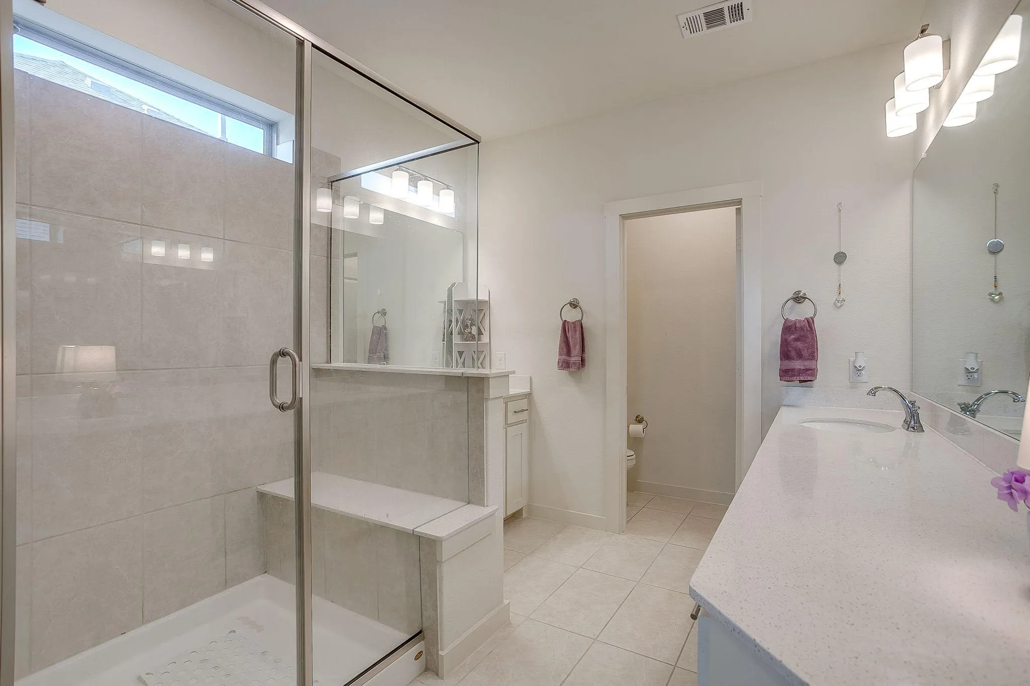 Primary bathroom: Glass-enclosed shower with a built-in bench and transom window