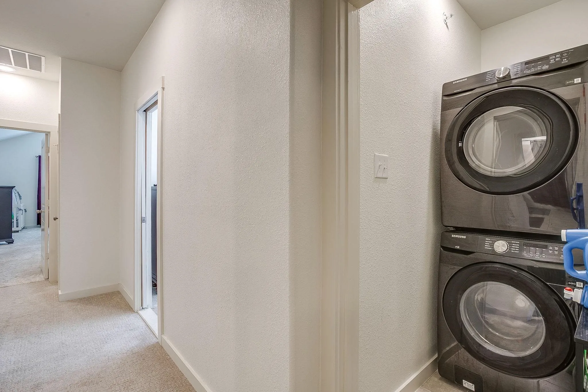 Stacked washer and dryer unit, neutral wall paint, and carpeted flooring