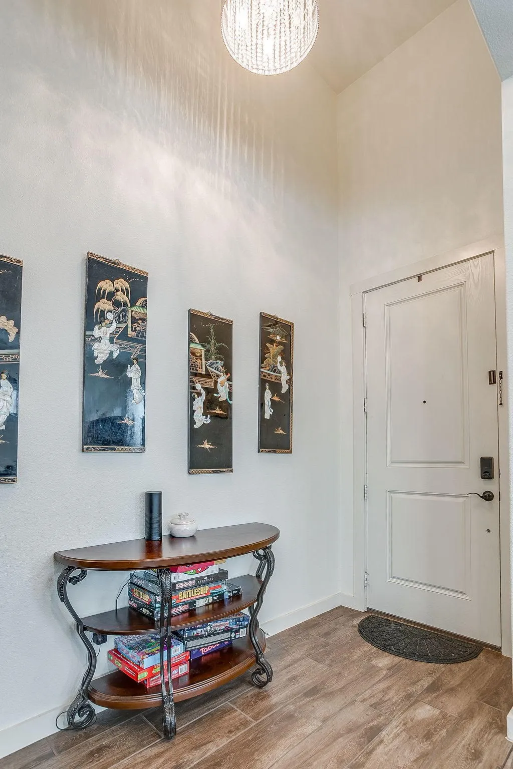 Recessed entryway with wood-finish flooring, a contemporary ceiling light fixture, and a paneled entry door with smart lock hardware