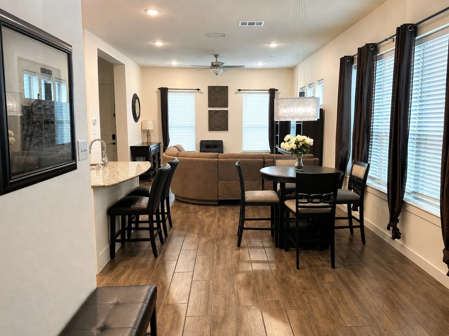 Open-concept living area with wood-finish flooring, recessed lighting, and a ceiling fan. Digitally decluttered.