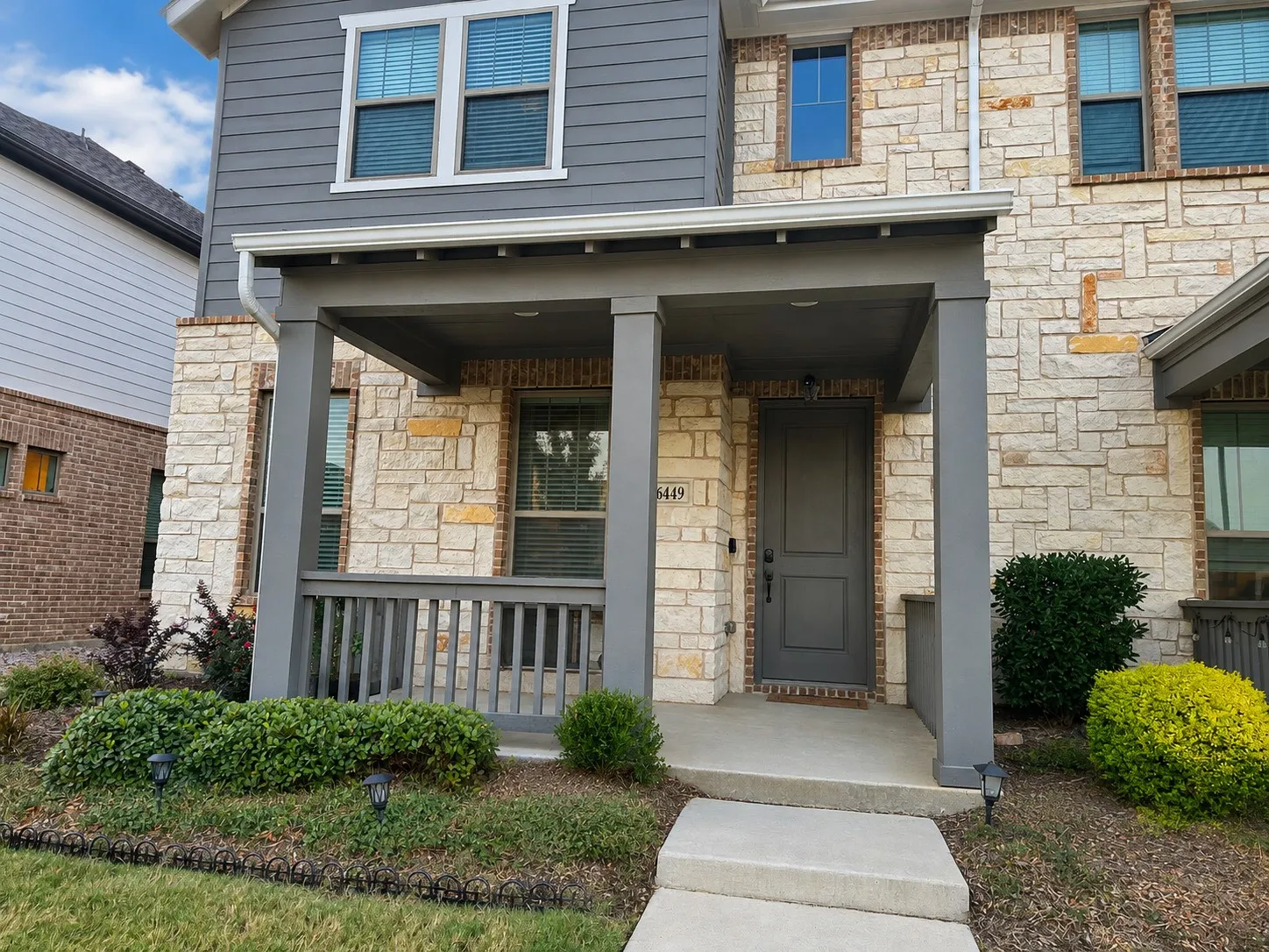 Front exterior featuring stone-and-siding construction and covered porch. Digitally declutterred.