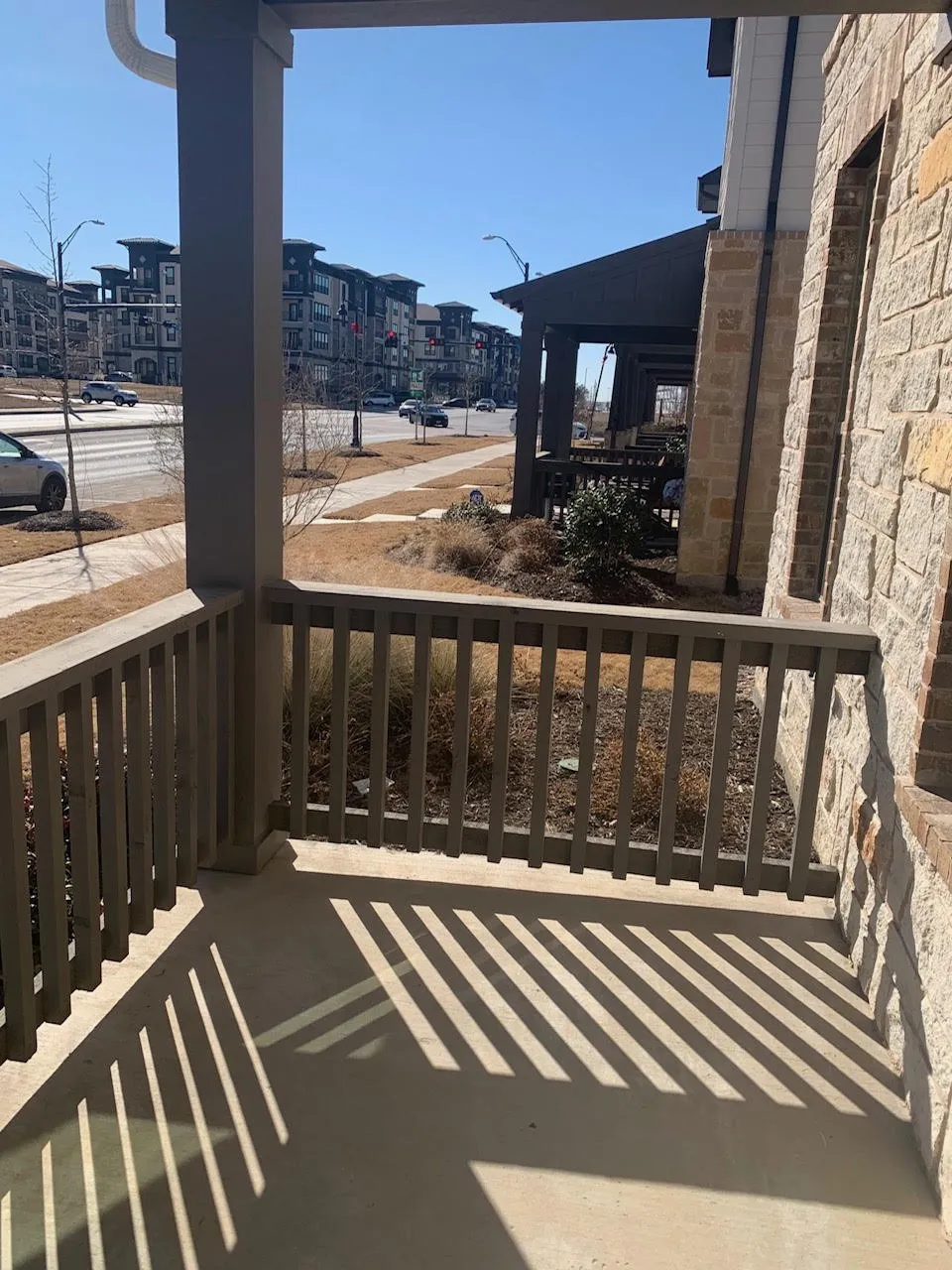 Covered porch with stone veneer siding and a wood railing