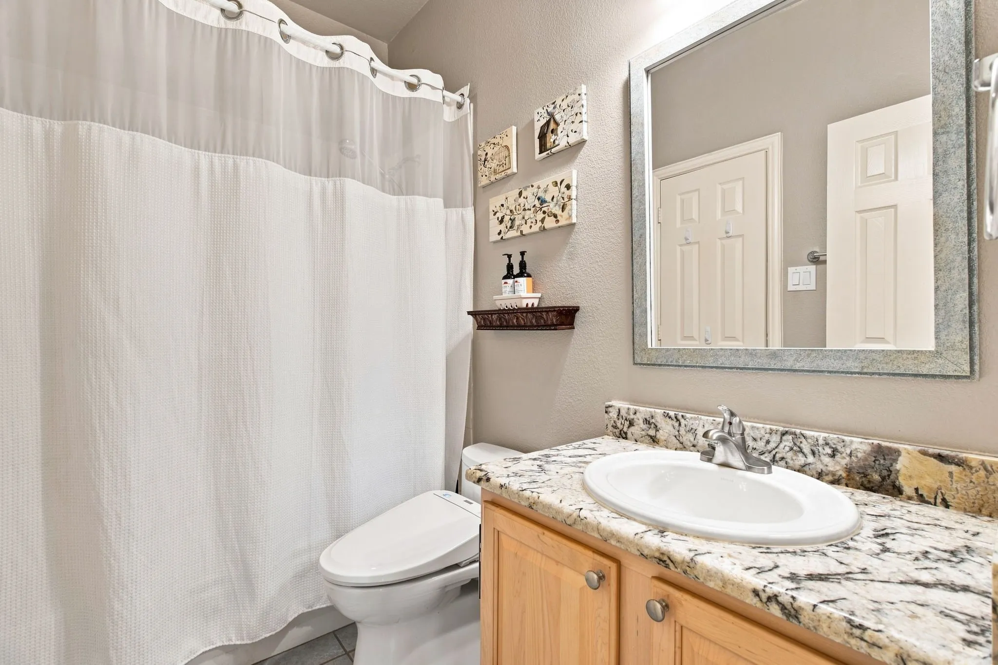 Vanity with stone countertop, undermount sink, and chrome faucet