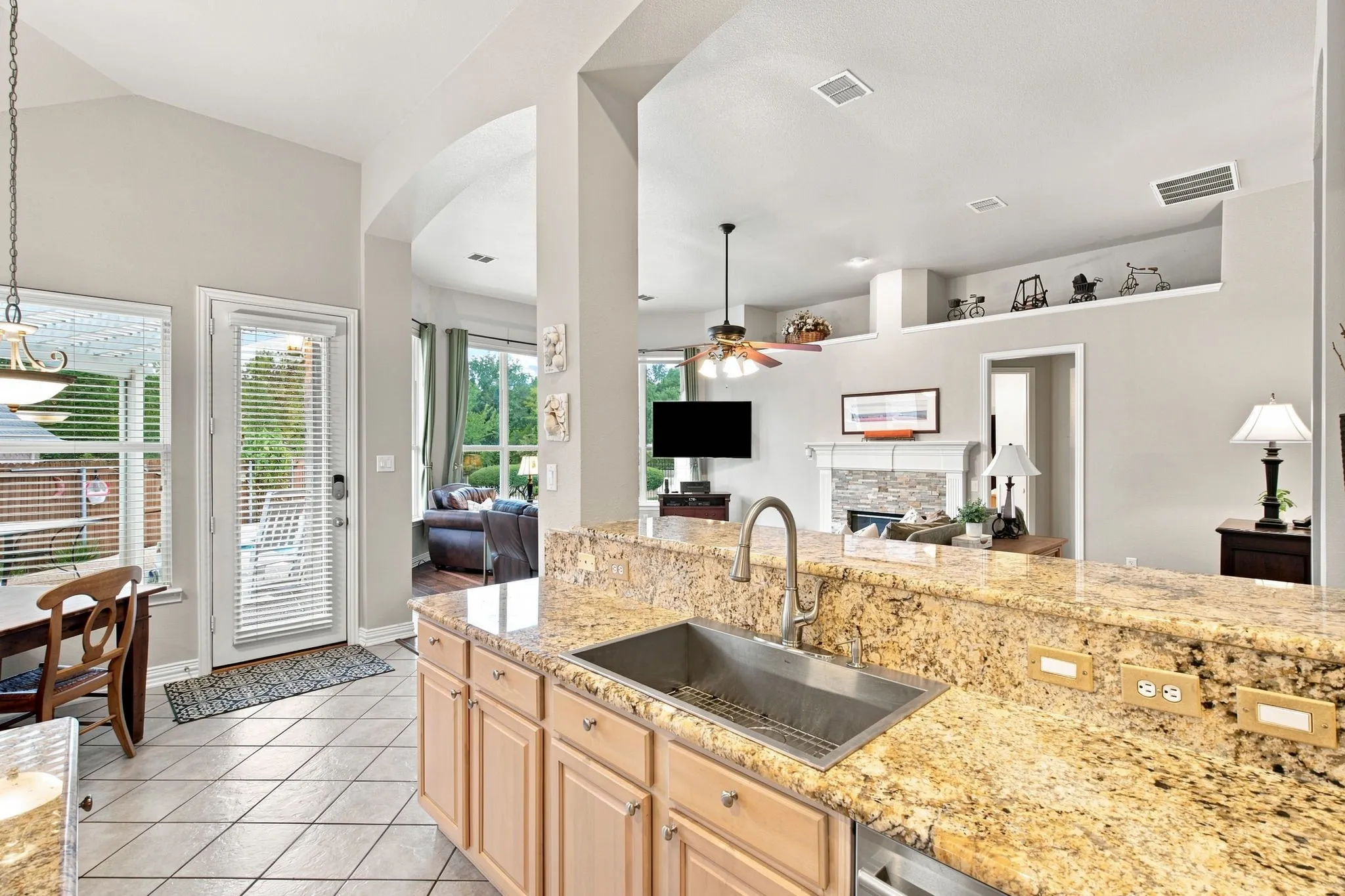 Kitchen with granite countertops, stainless steel undermount sink, light wood cabinetry, and tiled flooring