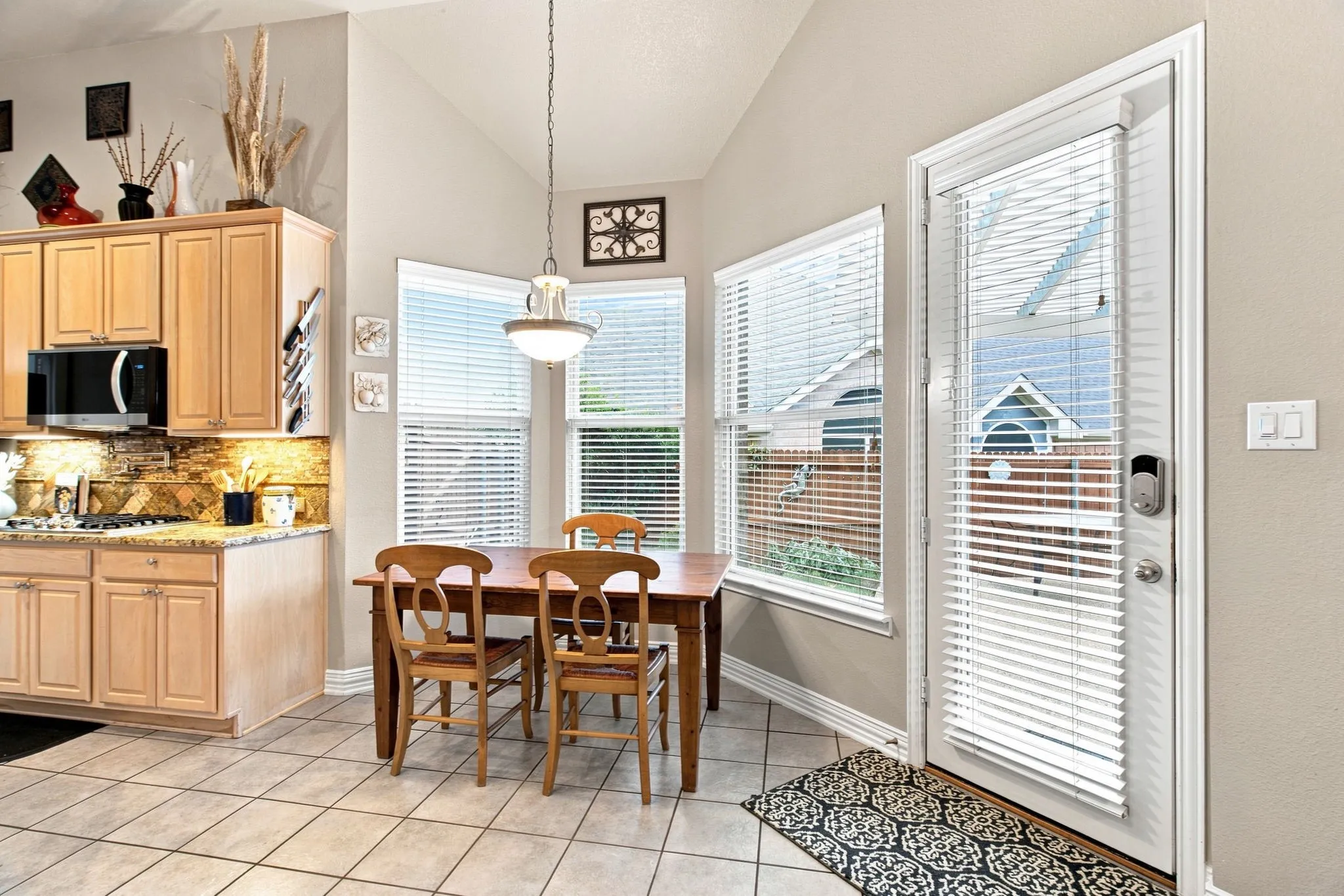 Kitchen with light wood-finish cabinetry, granite-style countertops, and a tile backsplash