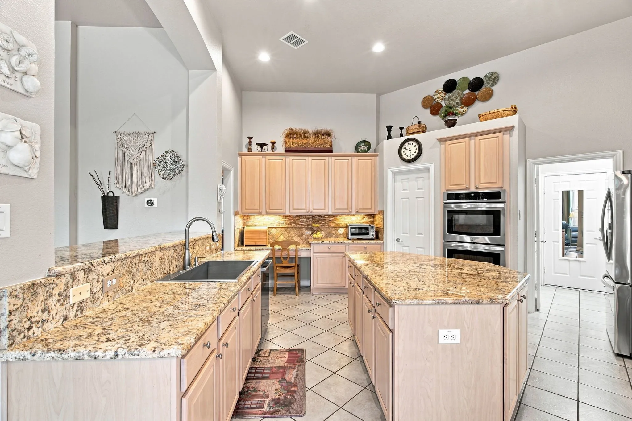 Kitchen featuring light wood-finish cabinetry, granite countertops, a double wall oven, and a center island