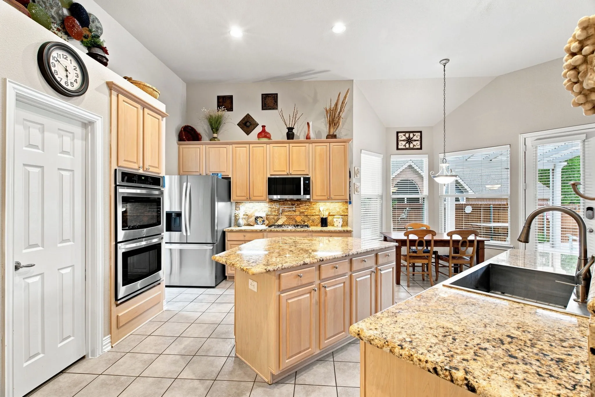 Vaulted ceilings, granite countertops, tile flooring, stainless steel appliances, and a kitchen island