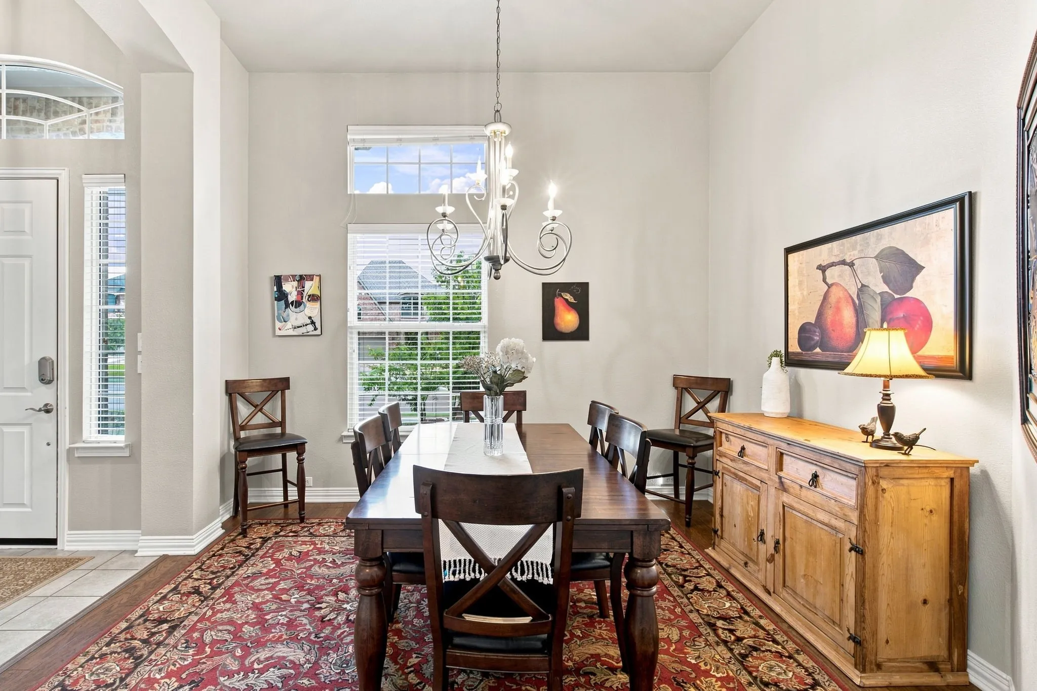 Dining space featuring high ceilings, wood-finish flooring, a decorative chandelier, and tall windows