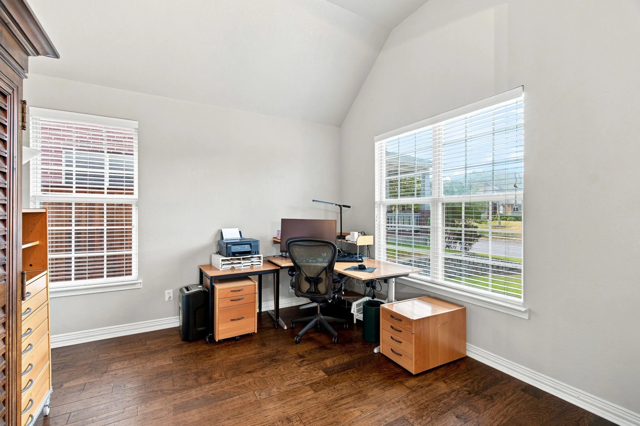 Vaulted ceiling, wood-finish flooring, and multiple windows with white blinds