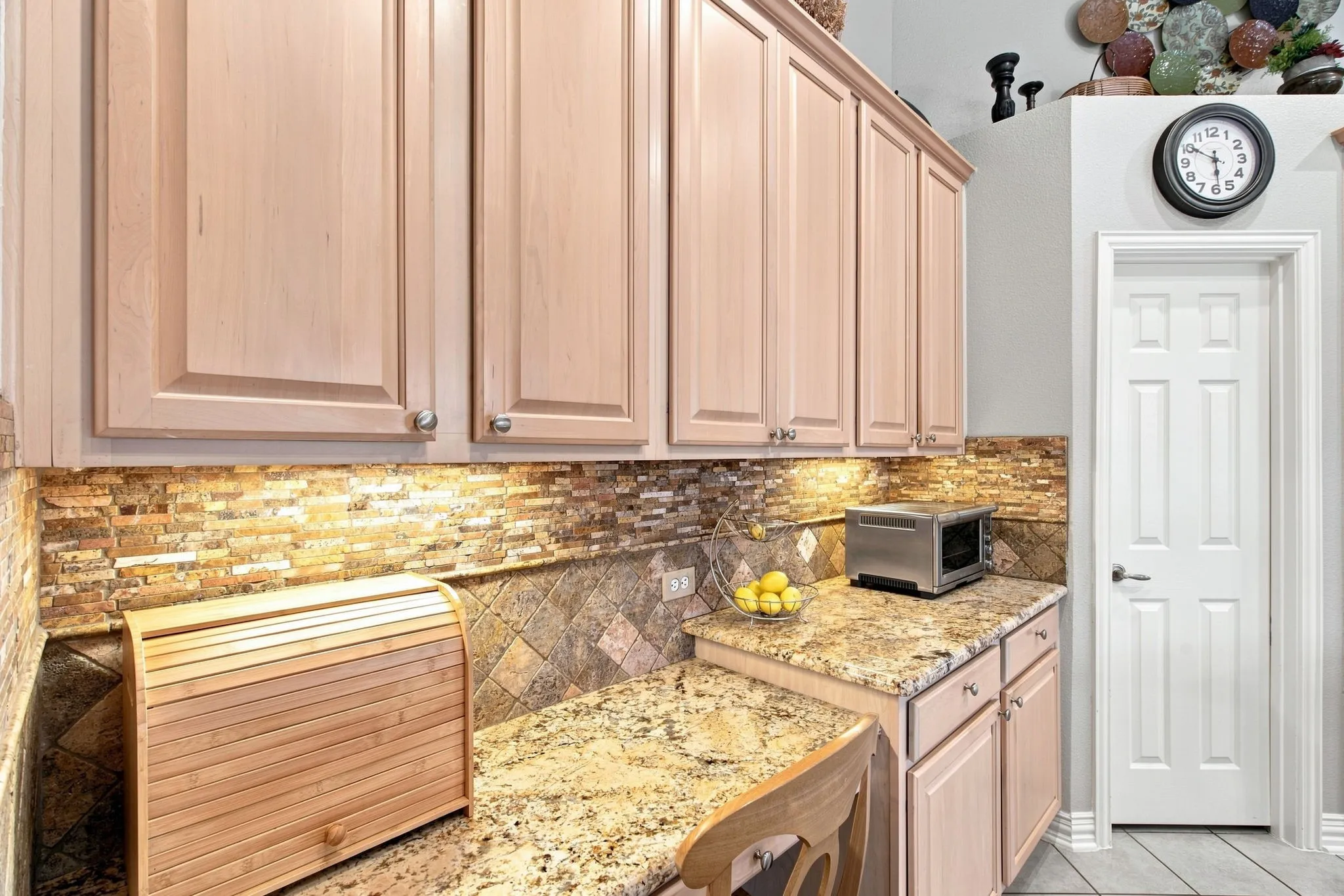 Upper and lower cabinetry with crown molding, granite countertops, stone tile backsplash, and under-cabinet lighting