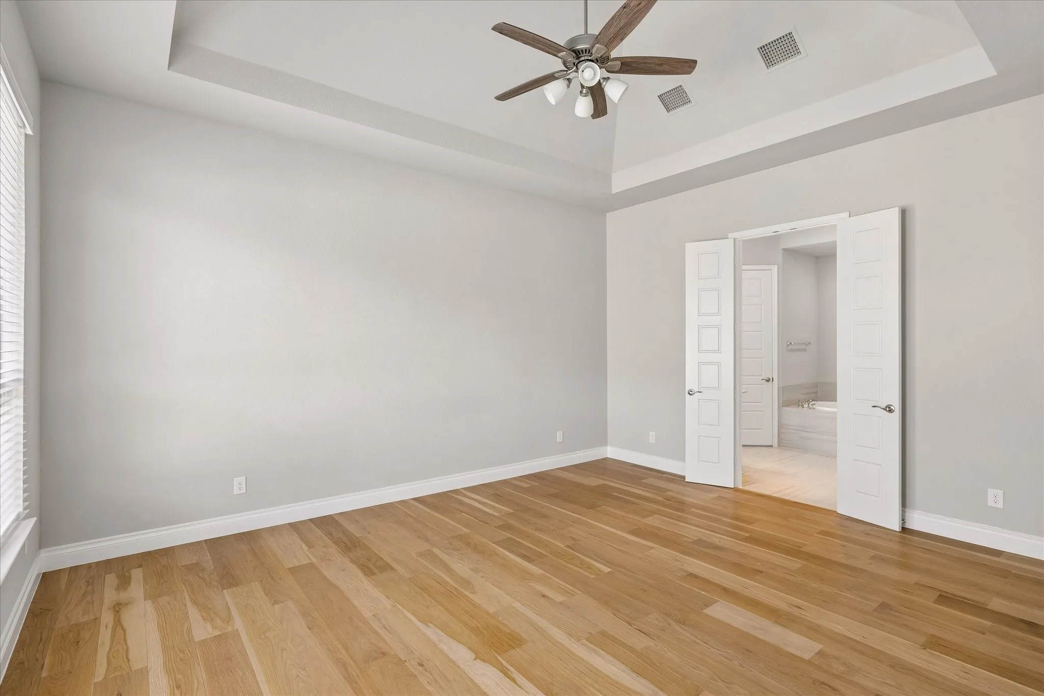 Primary bedroom with vaulted ceiling and French doors to primary bathroom