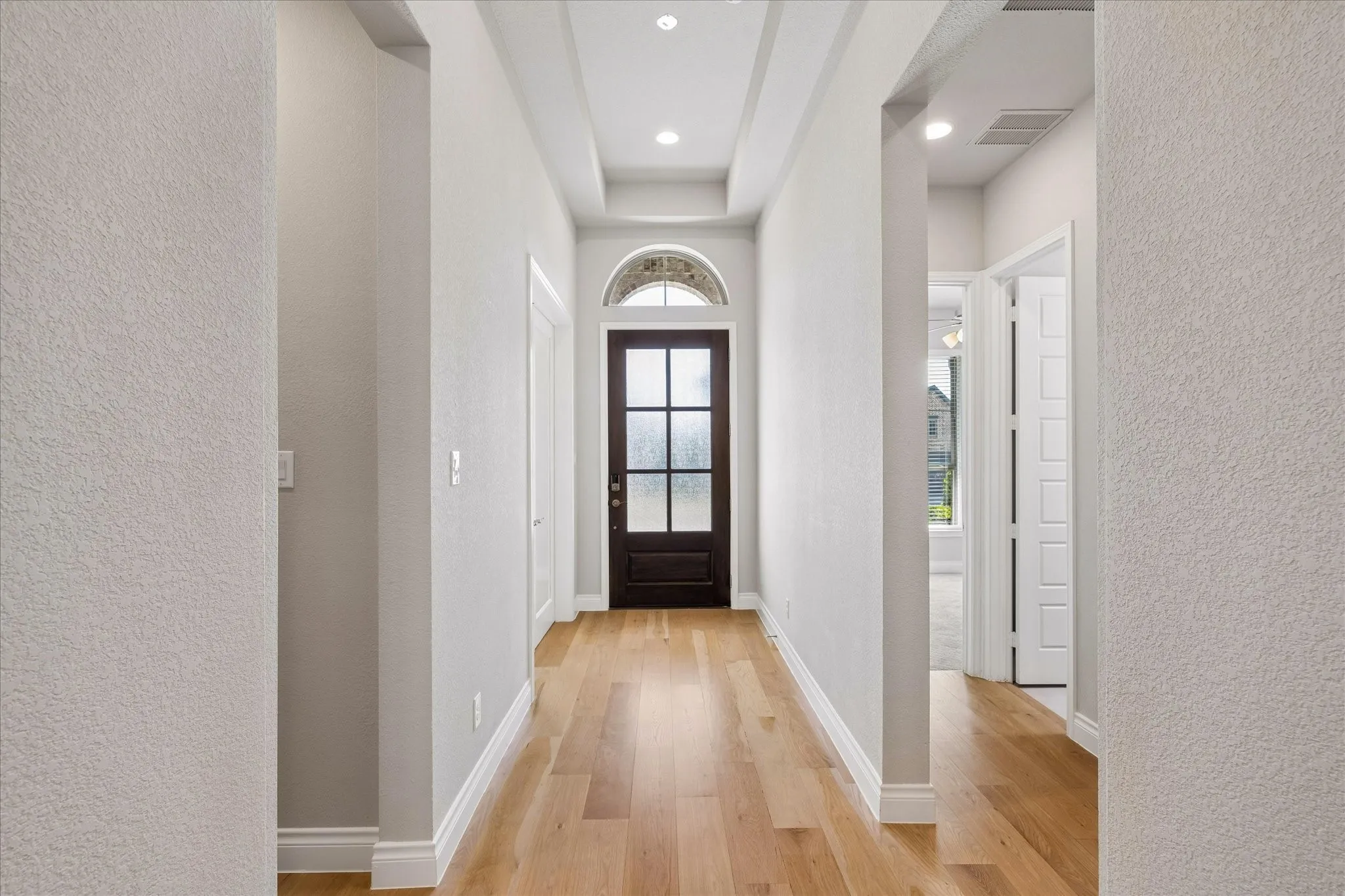 Entrance hallway with hall to garage and mud room to the left and hall to a full bathroom and two bedrooms on the right. Entry hall has trayed 12 ft ceiling.