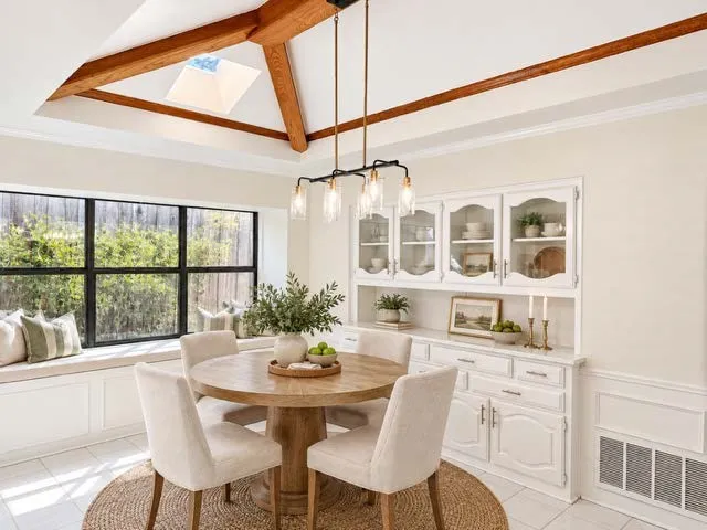 staged vaulted ceiling with exposed wood beams and skylight