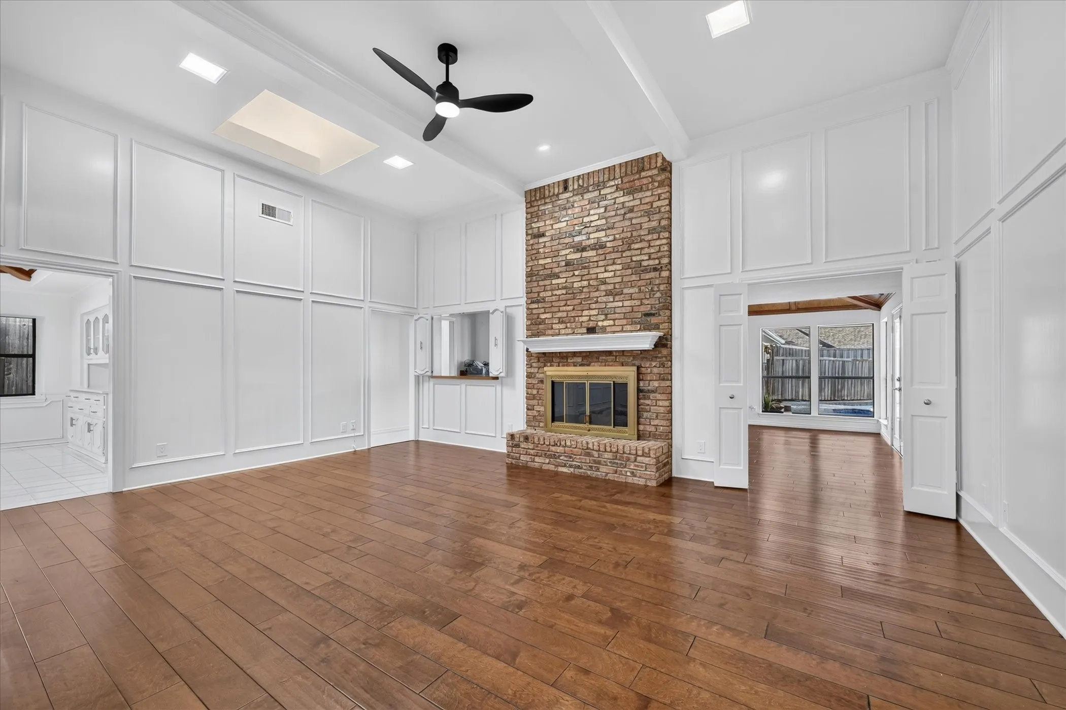 Wood-finish flooring with a brick-faced fireplace, a wood mantel, and a metal firebox