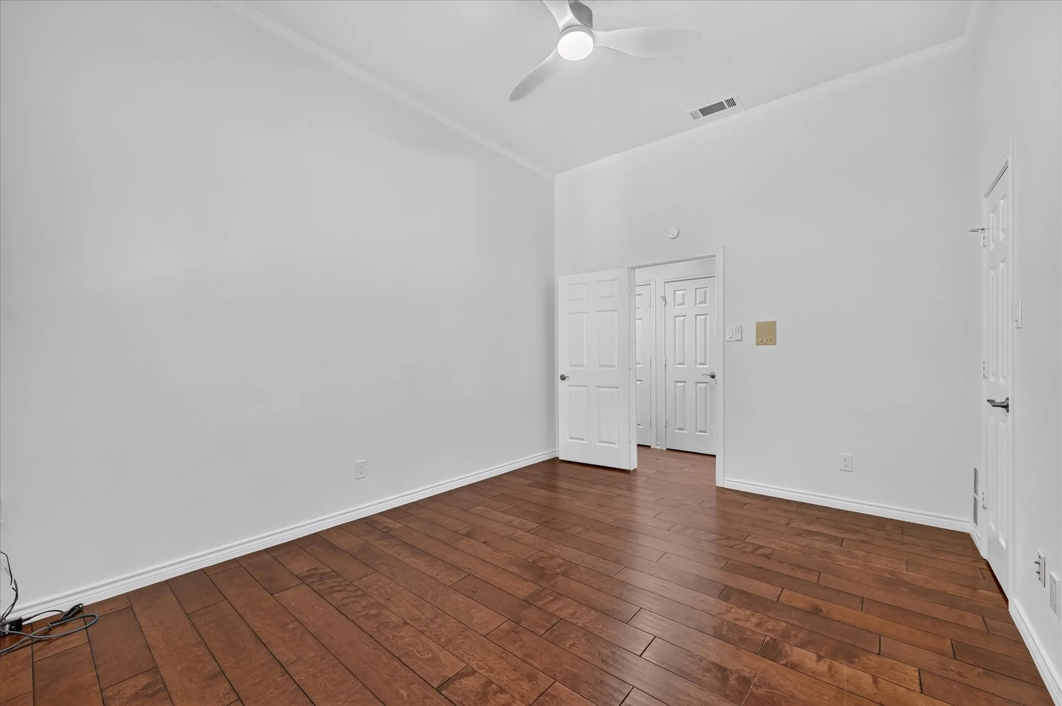Vaulted ceiling with a ceiling fan, wood-finish flooring, and white interior doors