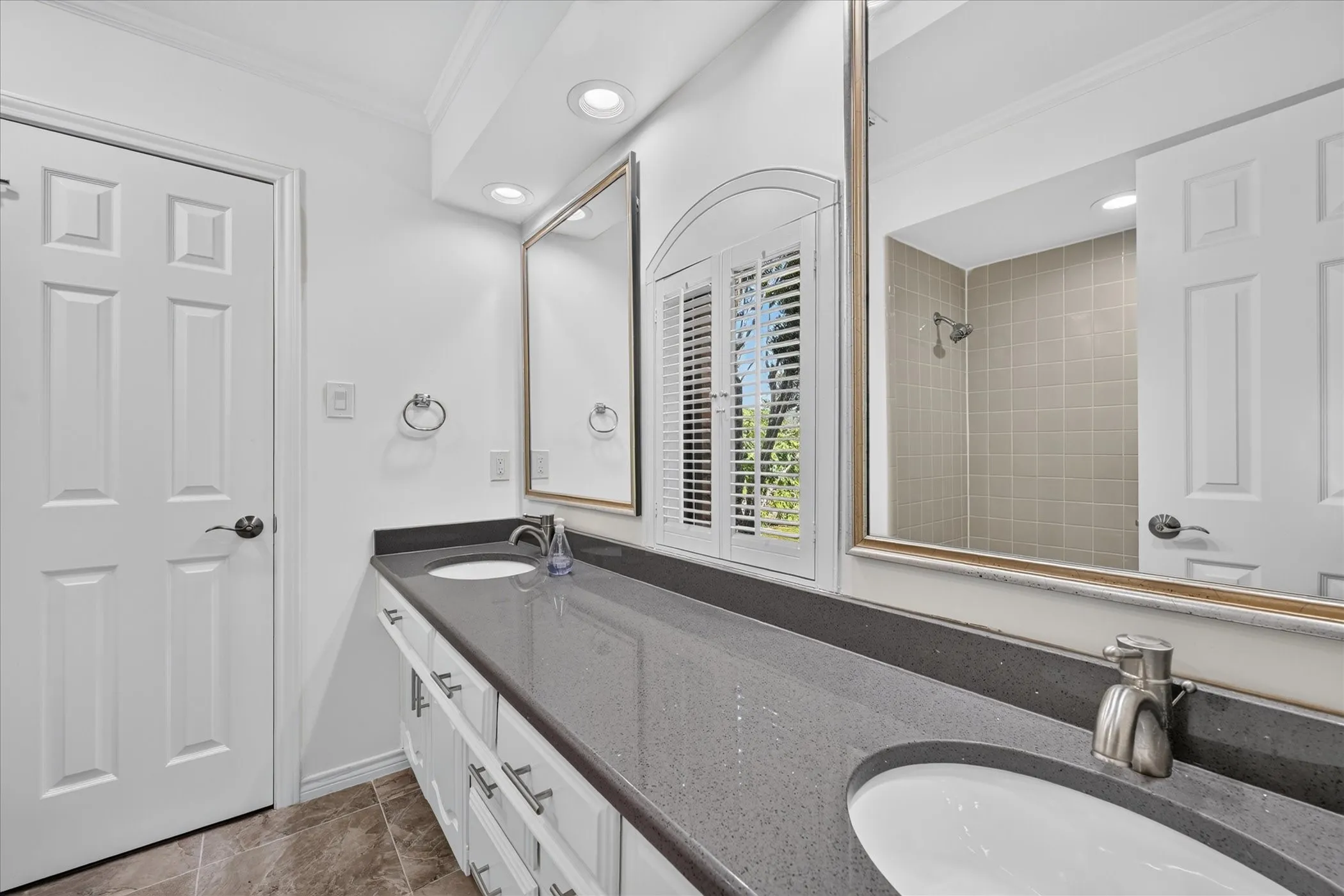 Dual vanity with integrated sinks, dark stone-finish countertop, and white cabinetry