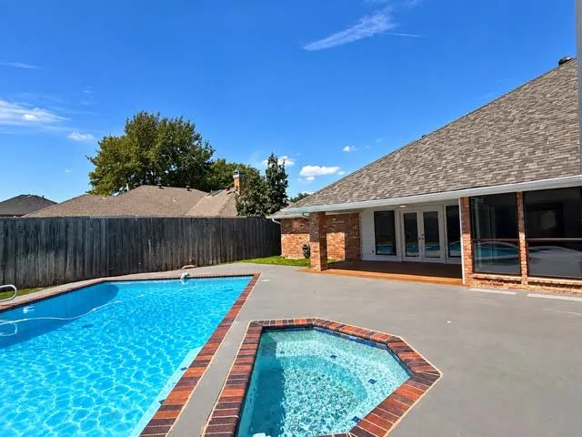Outdoor swimming pool and spa with extensive concrete patio, and deck