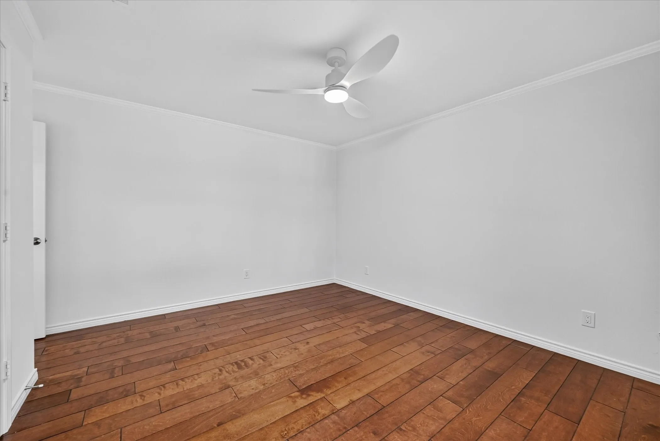 Hardwood flooring, crown molding, white walls, white ceiling fan with integrated lighting, and white trim