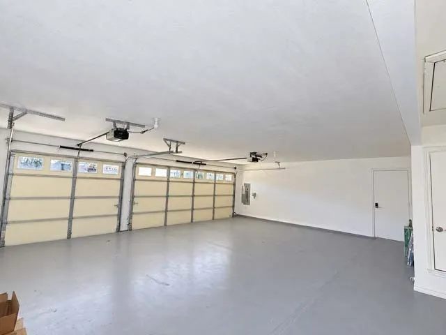 Three-car garage featuring a painted floor and two garage door openers