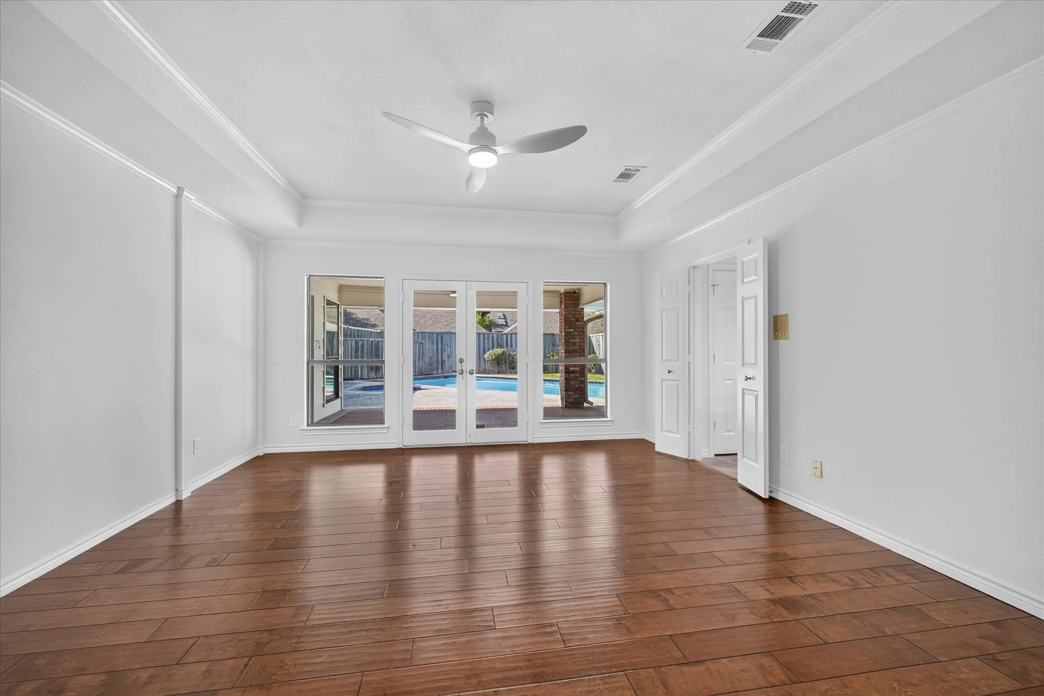 large primary bedroom, open to covered patio, wood-finish flooring  ceiling fan
