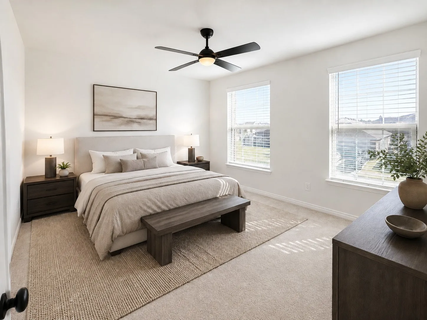 Upholstered headboard, two large windows, ceiling fan, and carpeted flooring