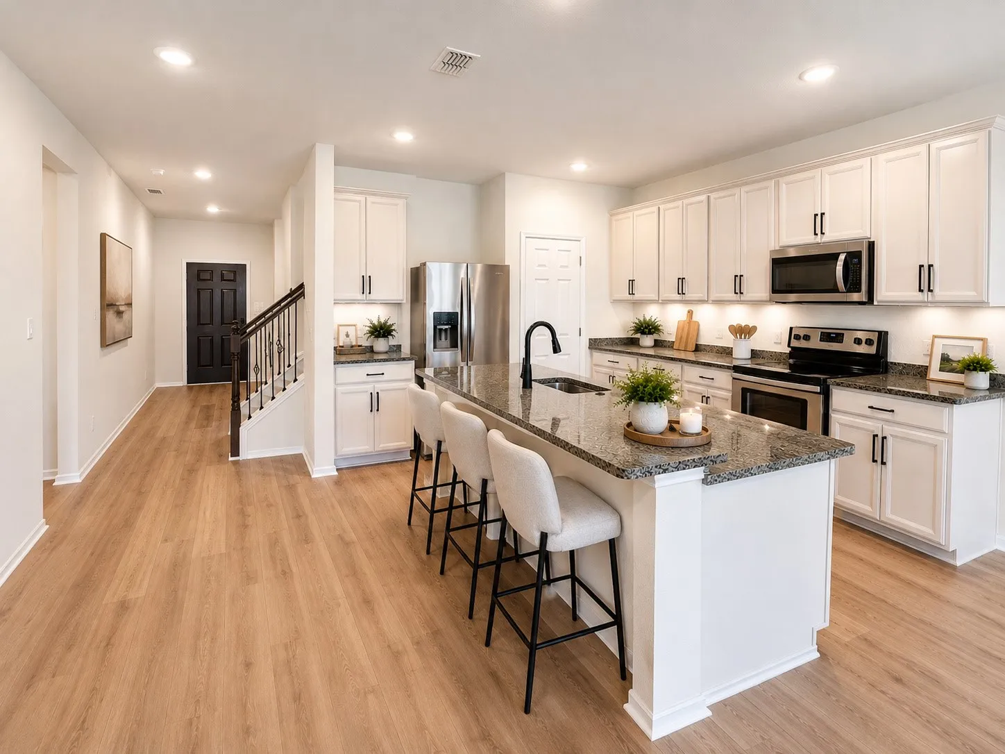 Open-concept kitchen with a central island, granite countertops, and white cabinetry
