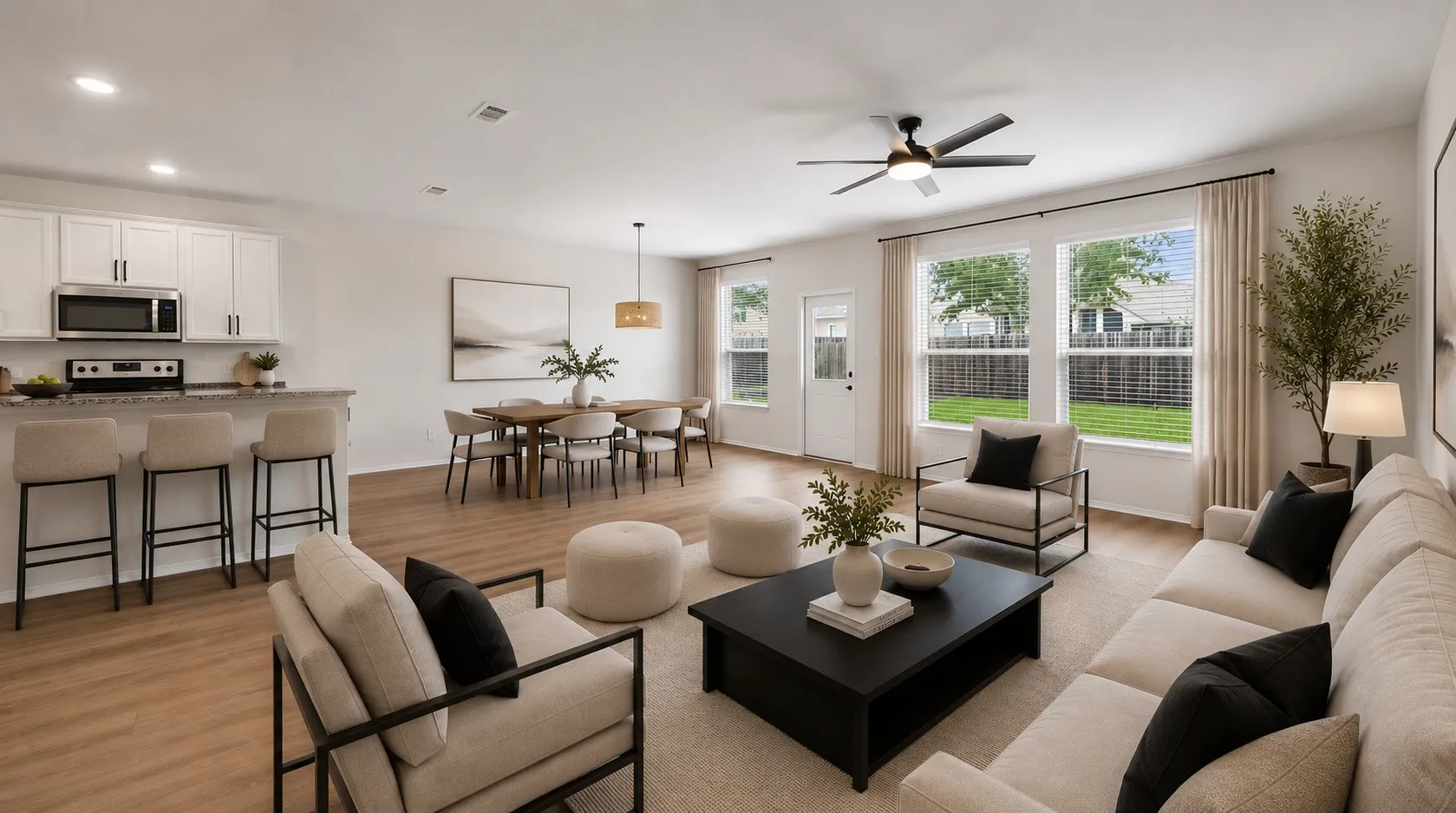 Open-concept living space featuring wood-finish flooring, a contemporary ceiling fan, and multiple large windows with blinds