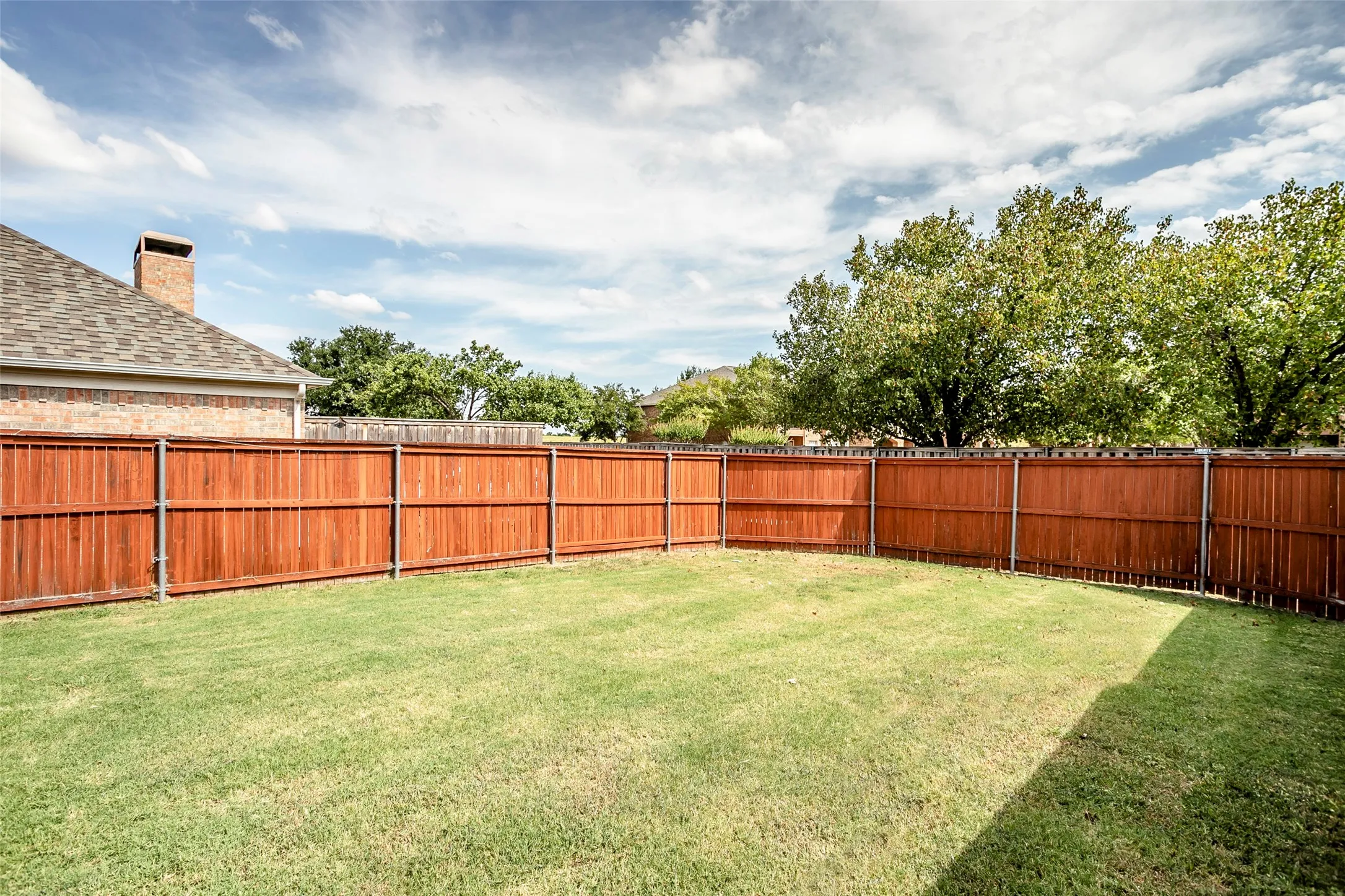Expansive grassy yard with full privacy fencing