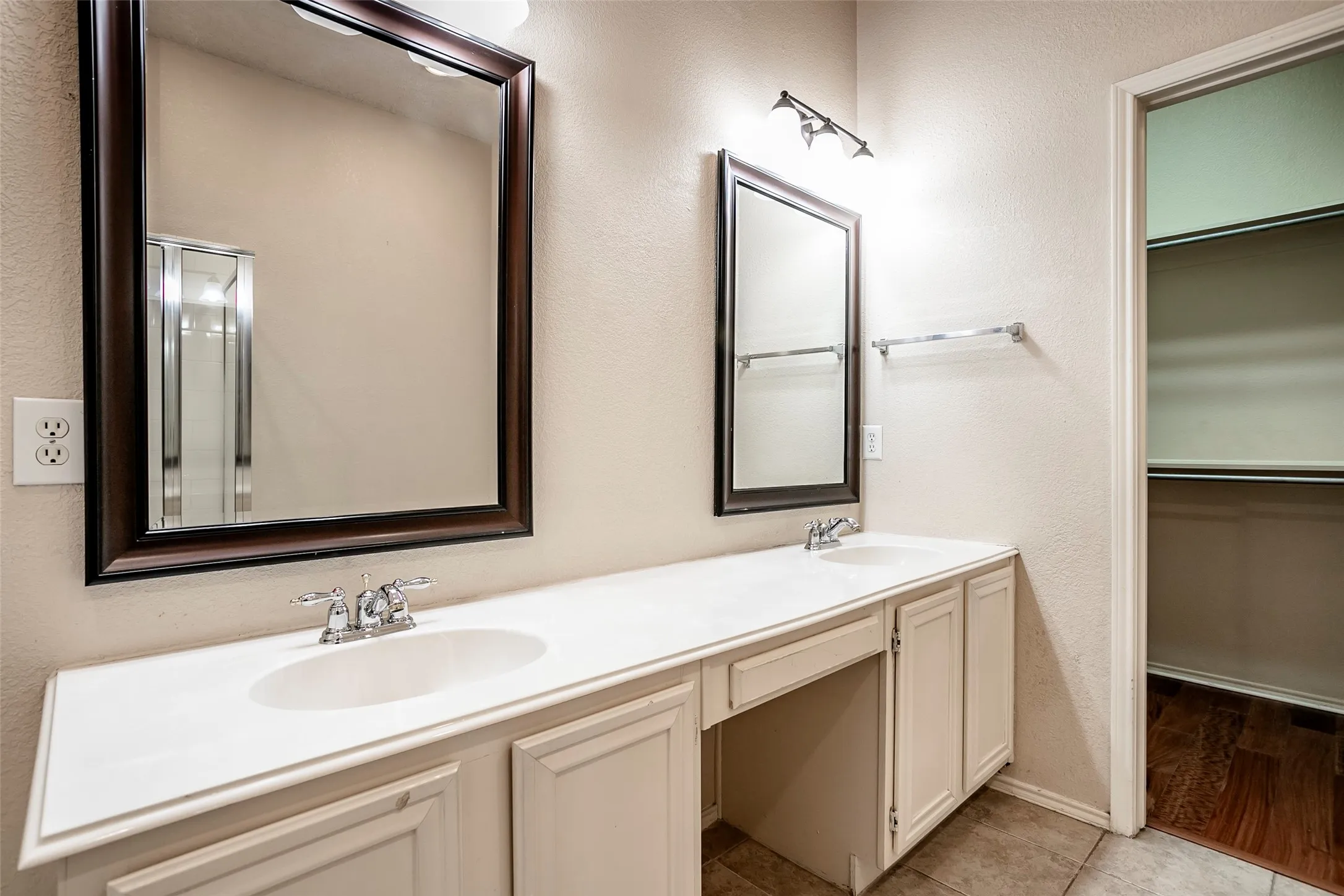 Dual vanity with white countertop, chrome fixtures, framed mirrors, and dedicated vanity space