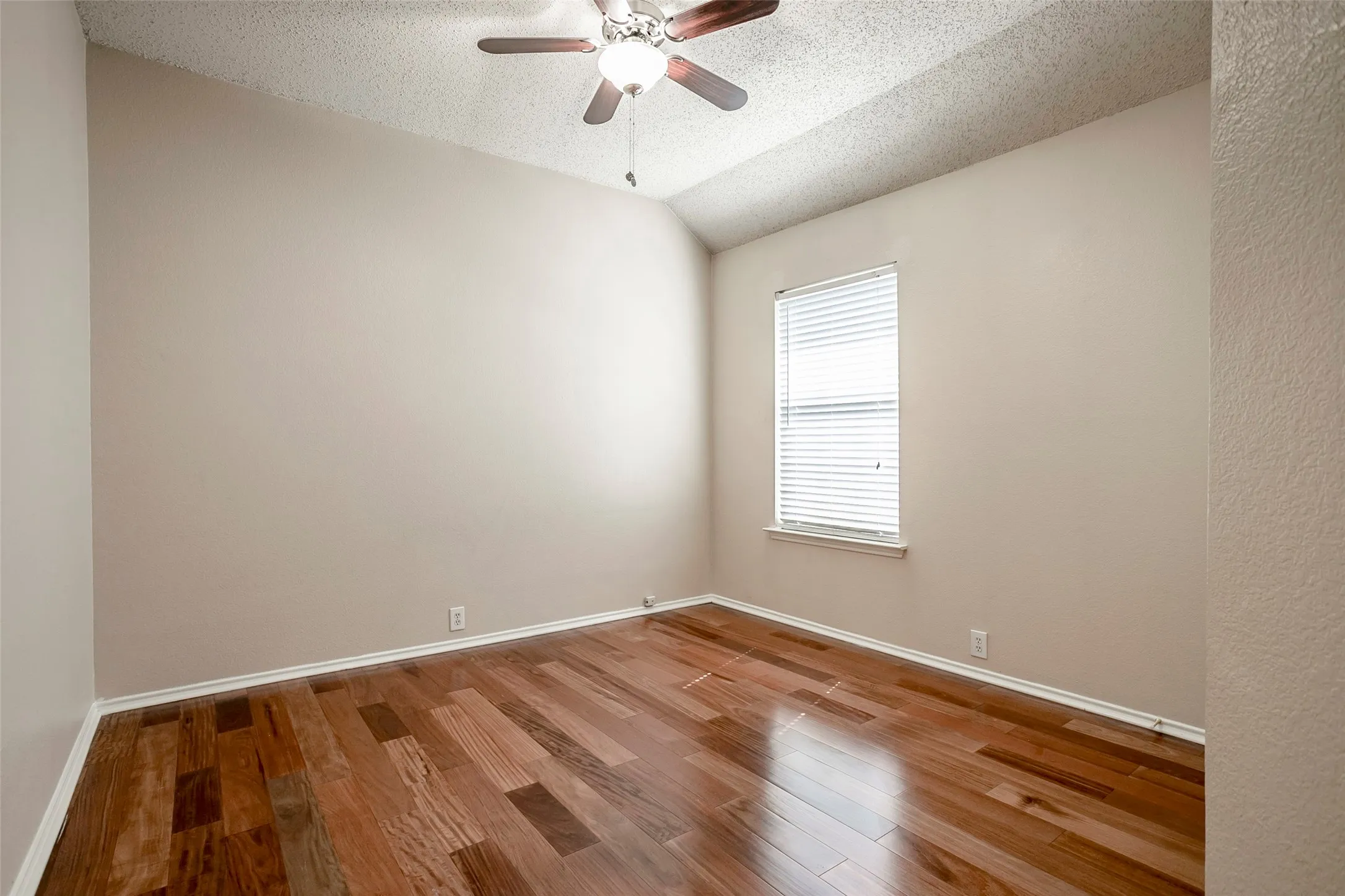 Vaulted ceiling with a ceiling fan, window with blinds, and wood-finish flooring