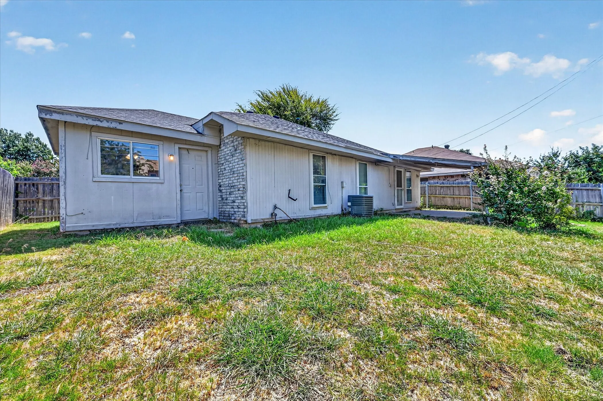 Expansive backyard featuring a partial privacy fence, mature landscaping, and a concrete patio