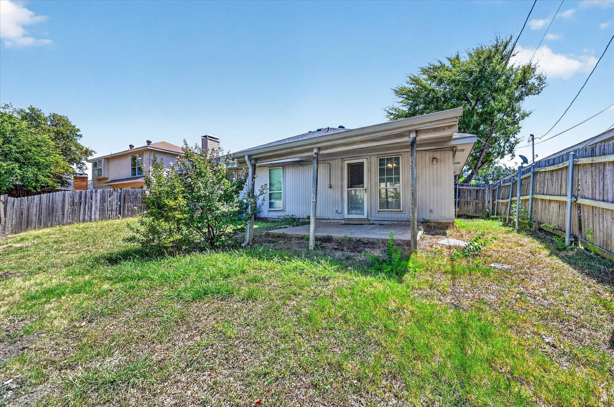 Rear exterior featuring a covered patio, dual-pane window, and wood privacy fencing