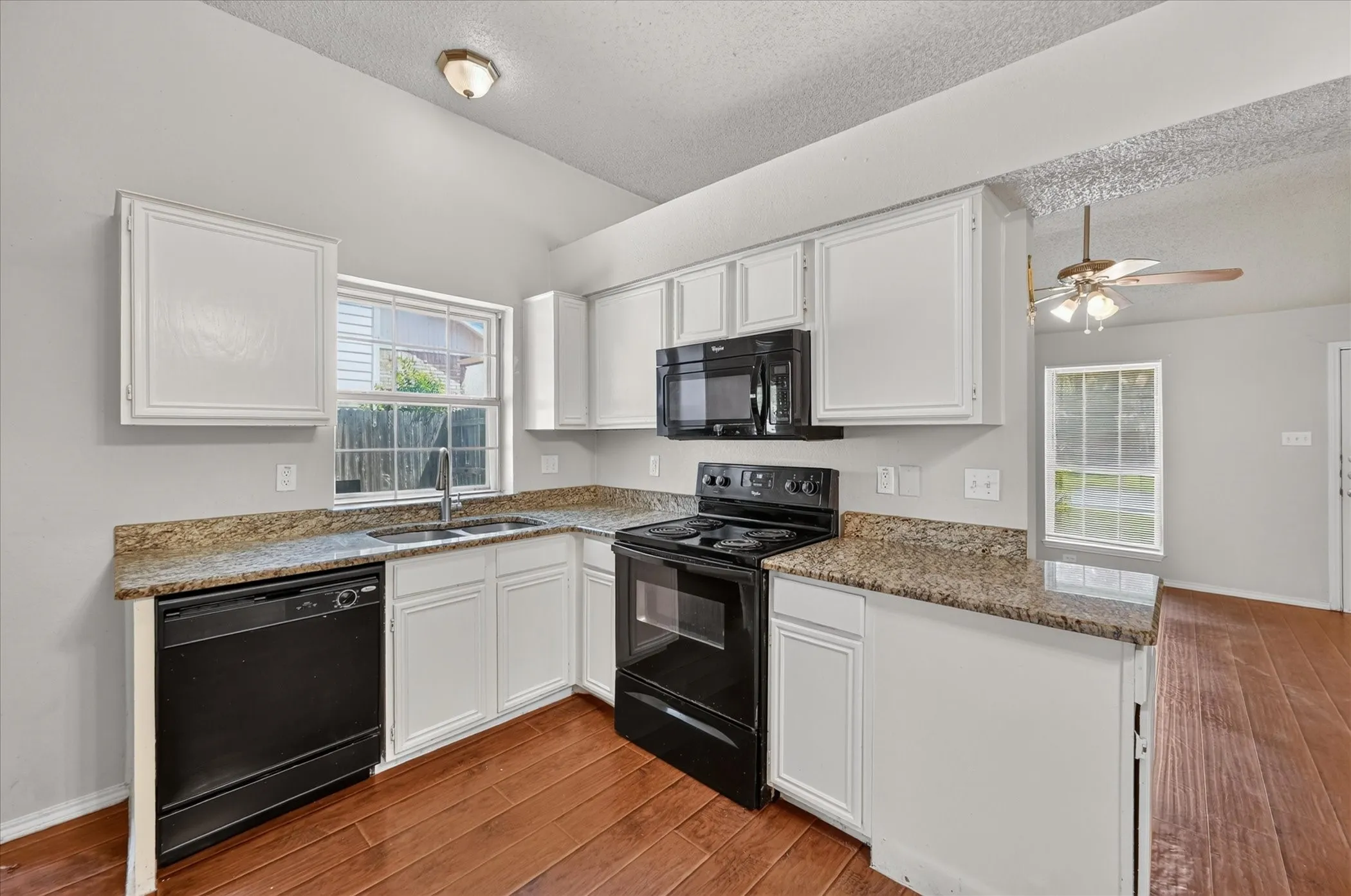 Kitchen with white cabinetry, a black appliance package, and wood-finish flooring