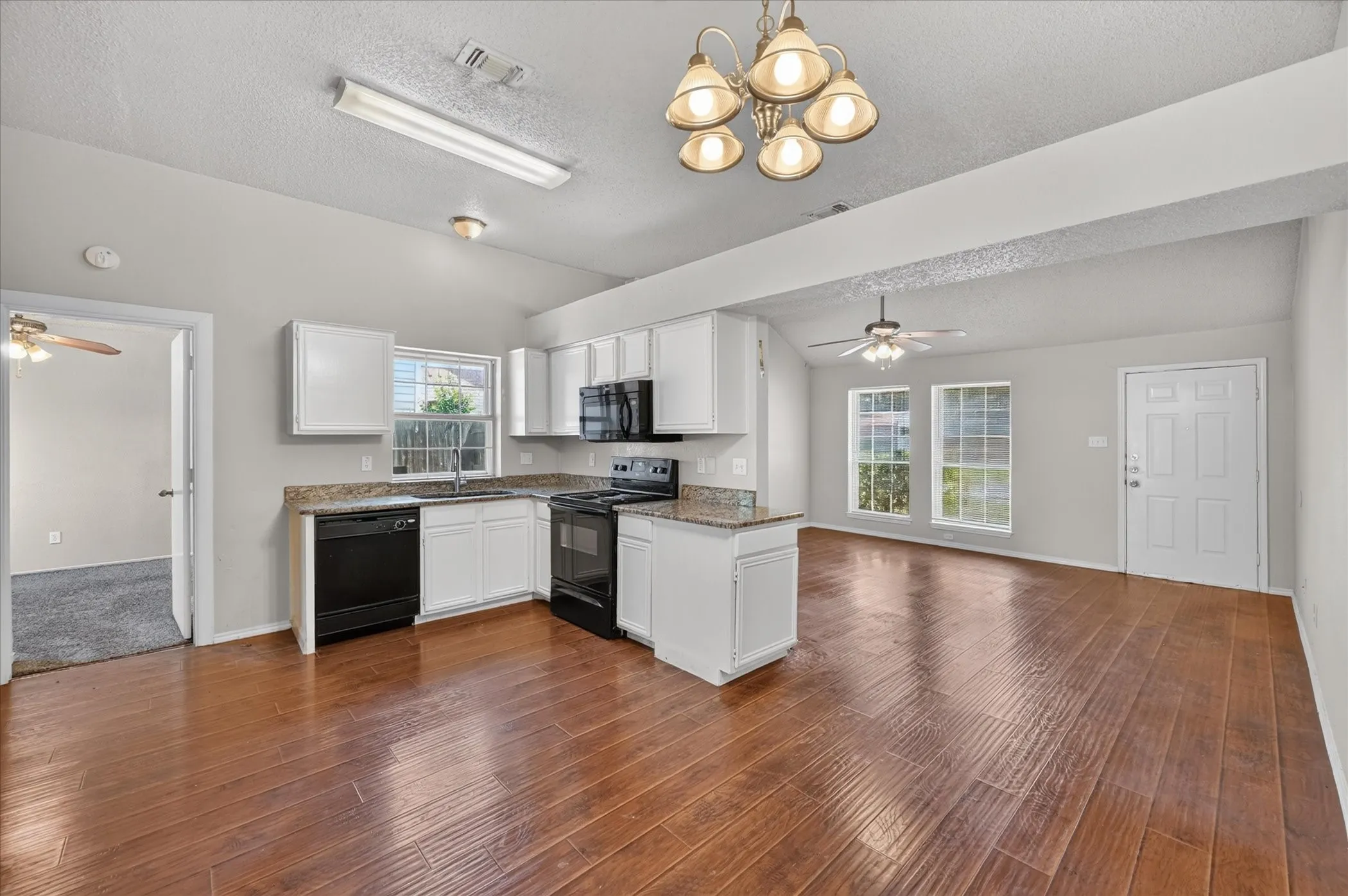 Kitchen with white cabinetry, granite-style countertops, and integrated black appliances