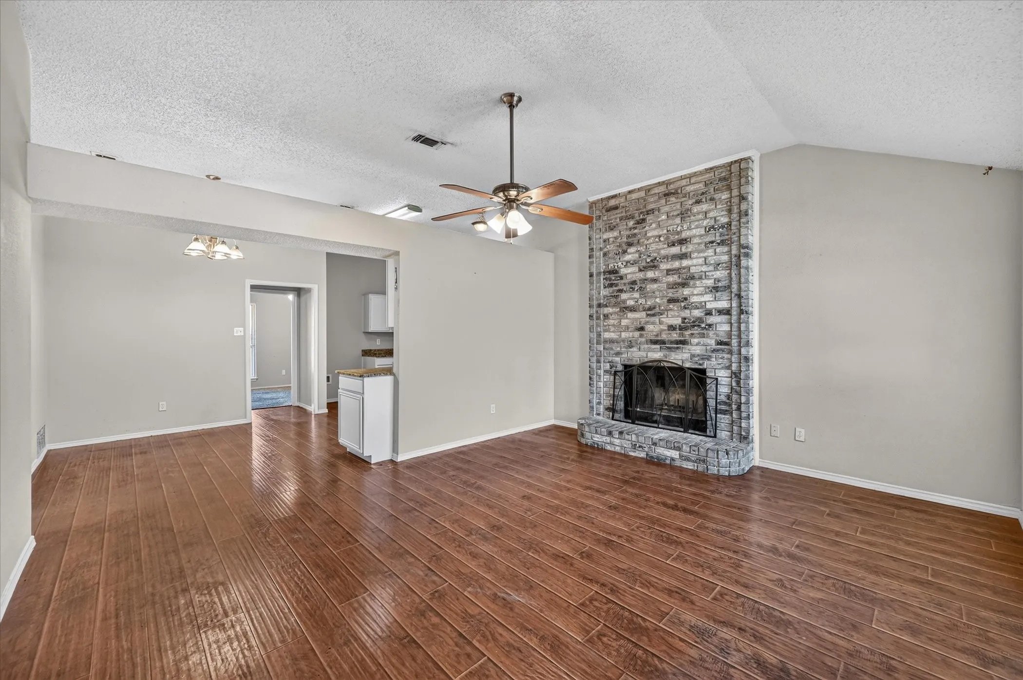Wood-finish flooring, vaulted ceiling, and a brick fireplace