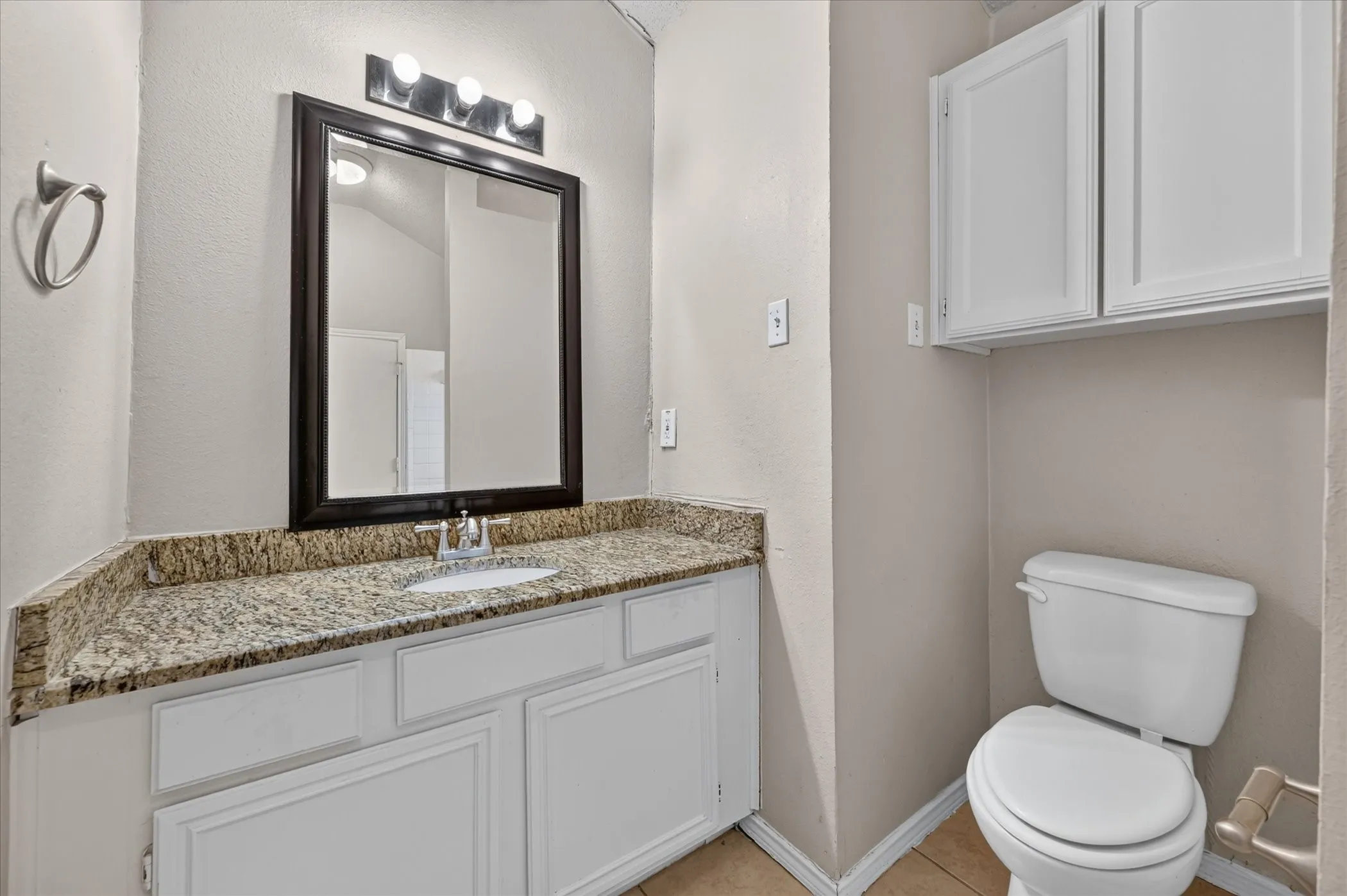 Vanity with a granite-style countertop, undermount sink, and chrome faucet