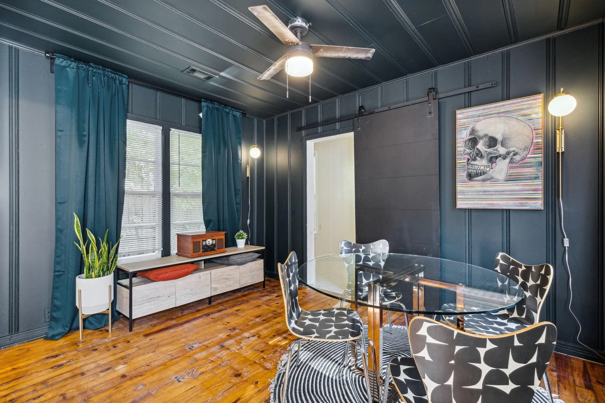 Wood-finish flooring, paneled walls and ceiling, and a ceiling fan with integrated lighting