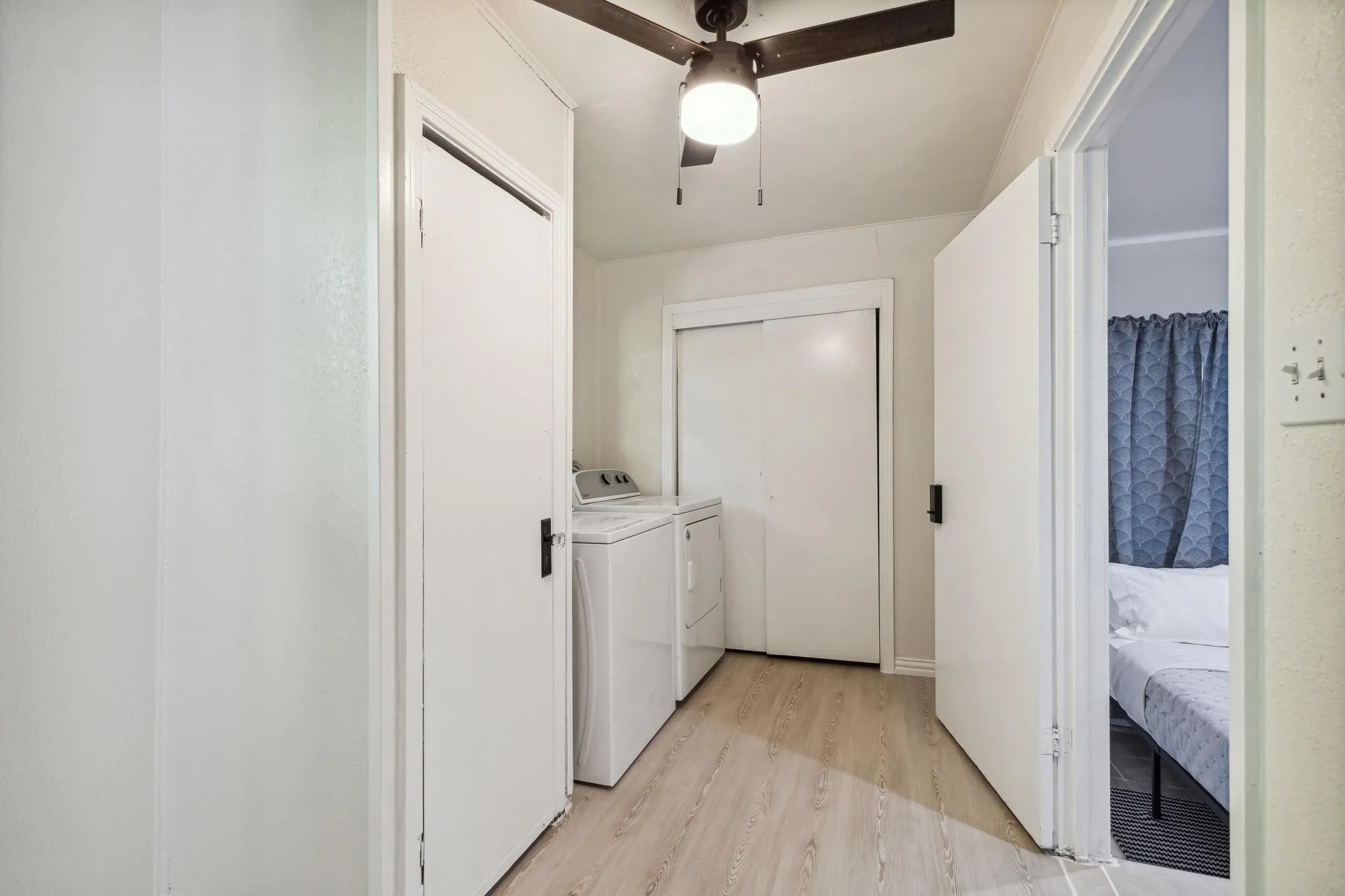 Dedicated laundry area featuring a washer and dryer, wood-finish flooring, and a ceiling fan with integrated lighting
